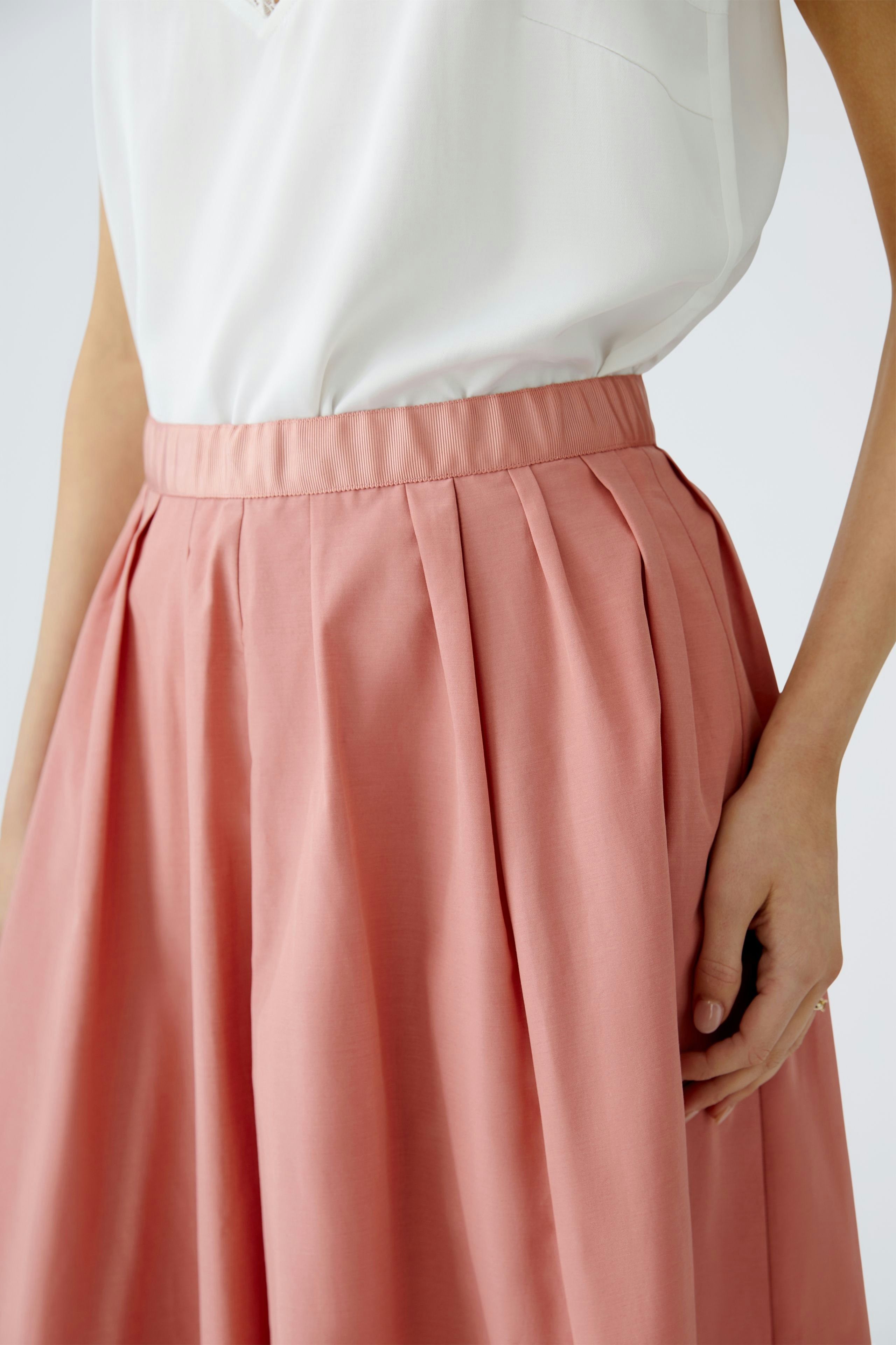 Elegant maxi skirt: A woman showcases a soft pink pleated maxi skirt, perfect for any occasion.