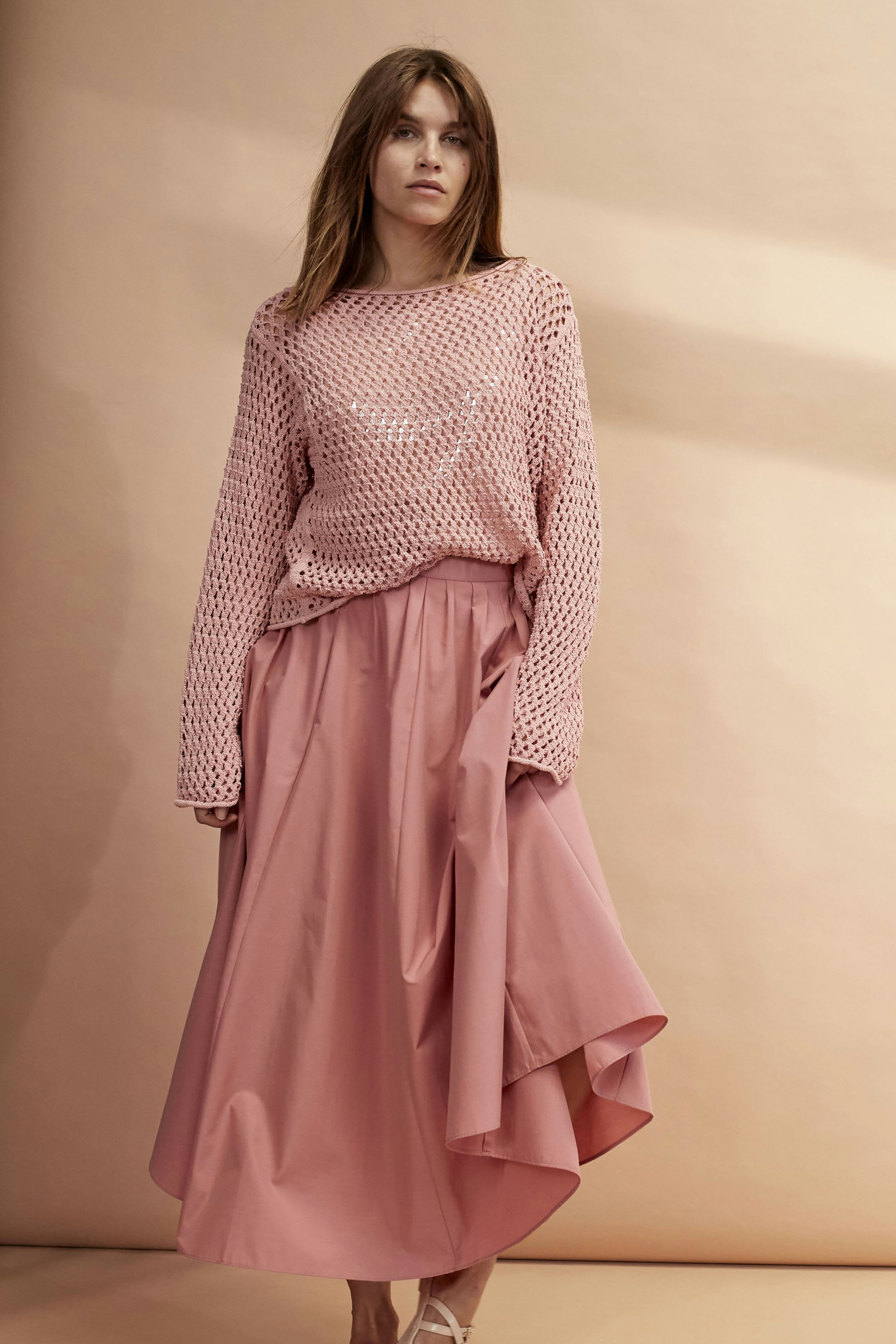 Elegant maxi skirt: A woman in a flowing pink maxi skirt, paired with a stylish pullover.