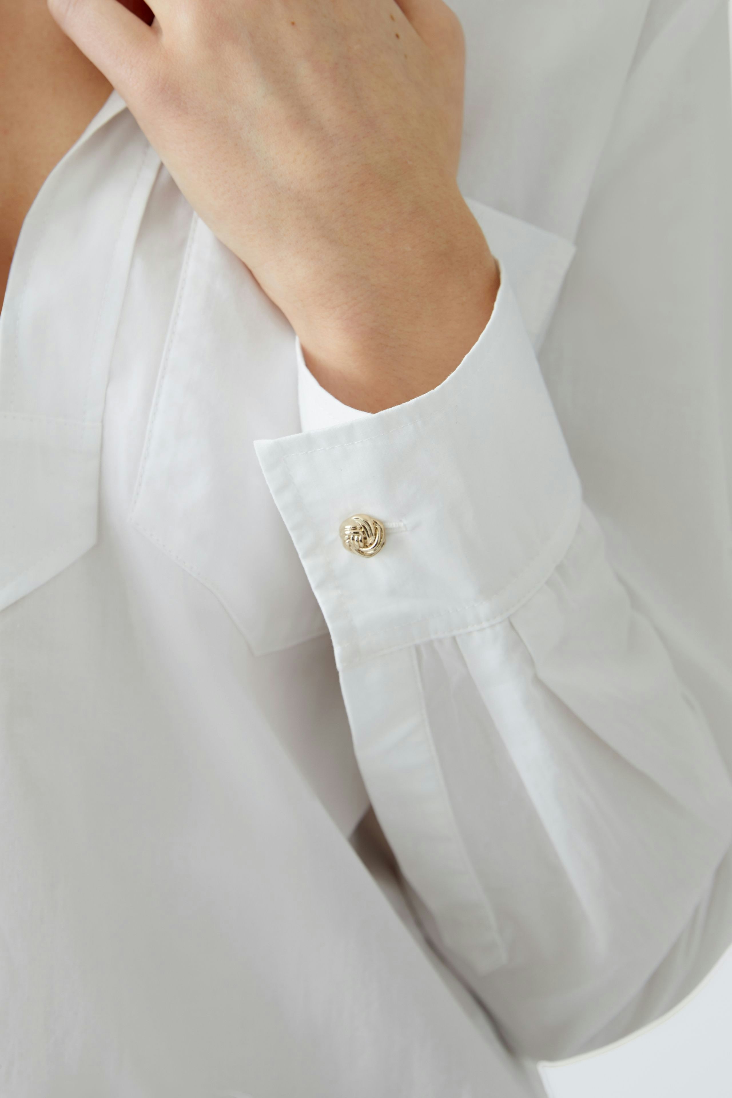 Elegante Damen-Bluse: Frau trägt eine weiße Bluse mit feinen Details und einem klassischen Schnitt.