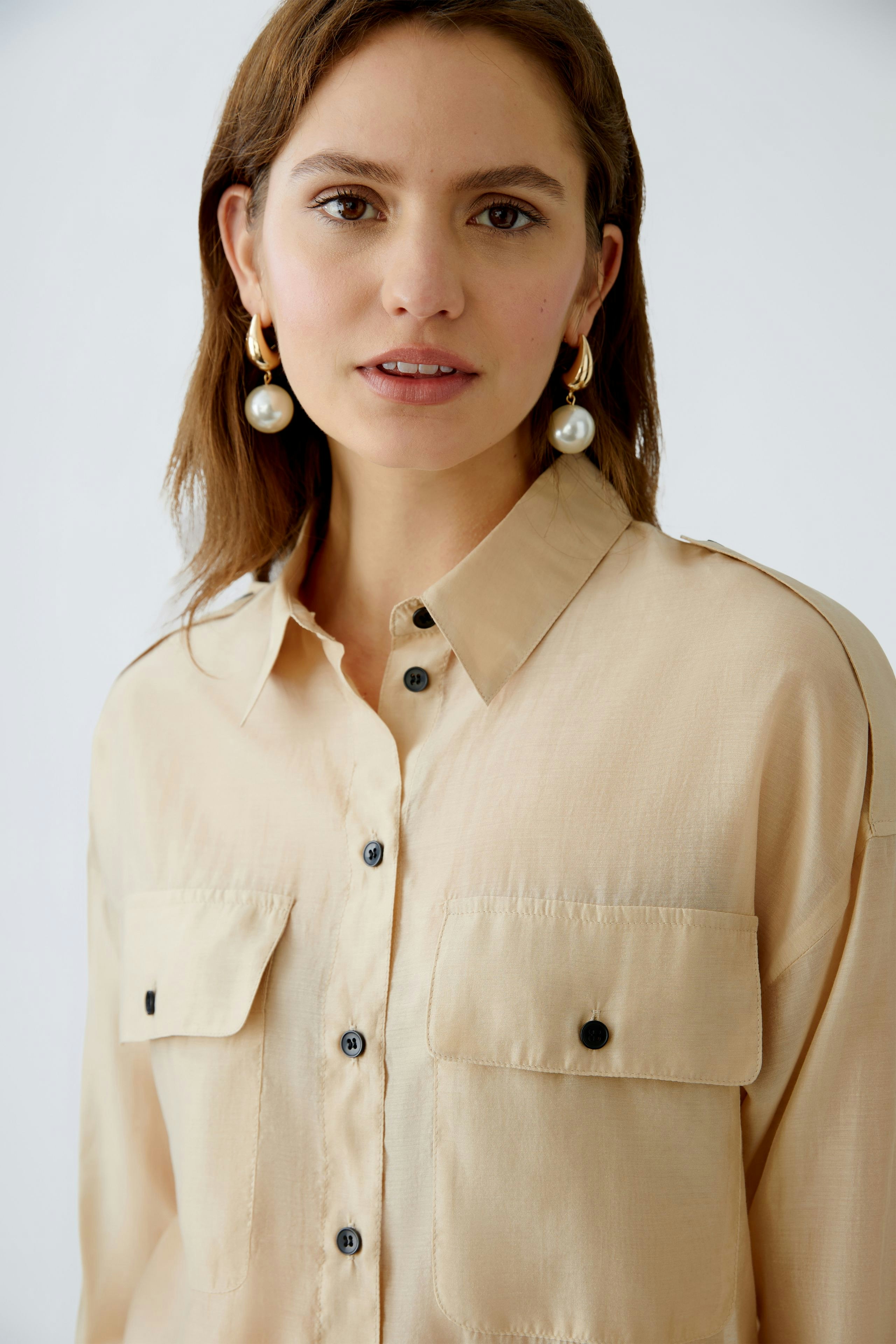 Stylish women's blouse: A woman in a light beige blouse with pockets, exuding elegance and comfort.