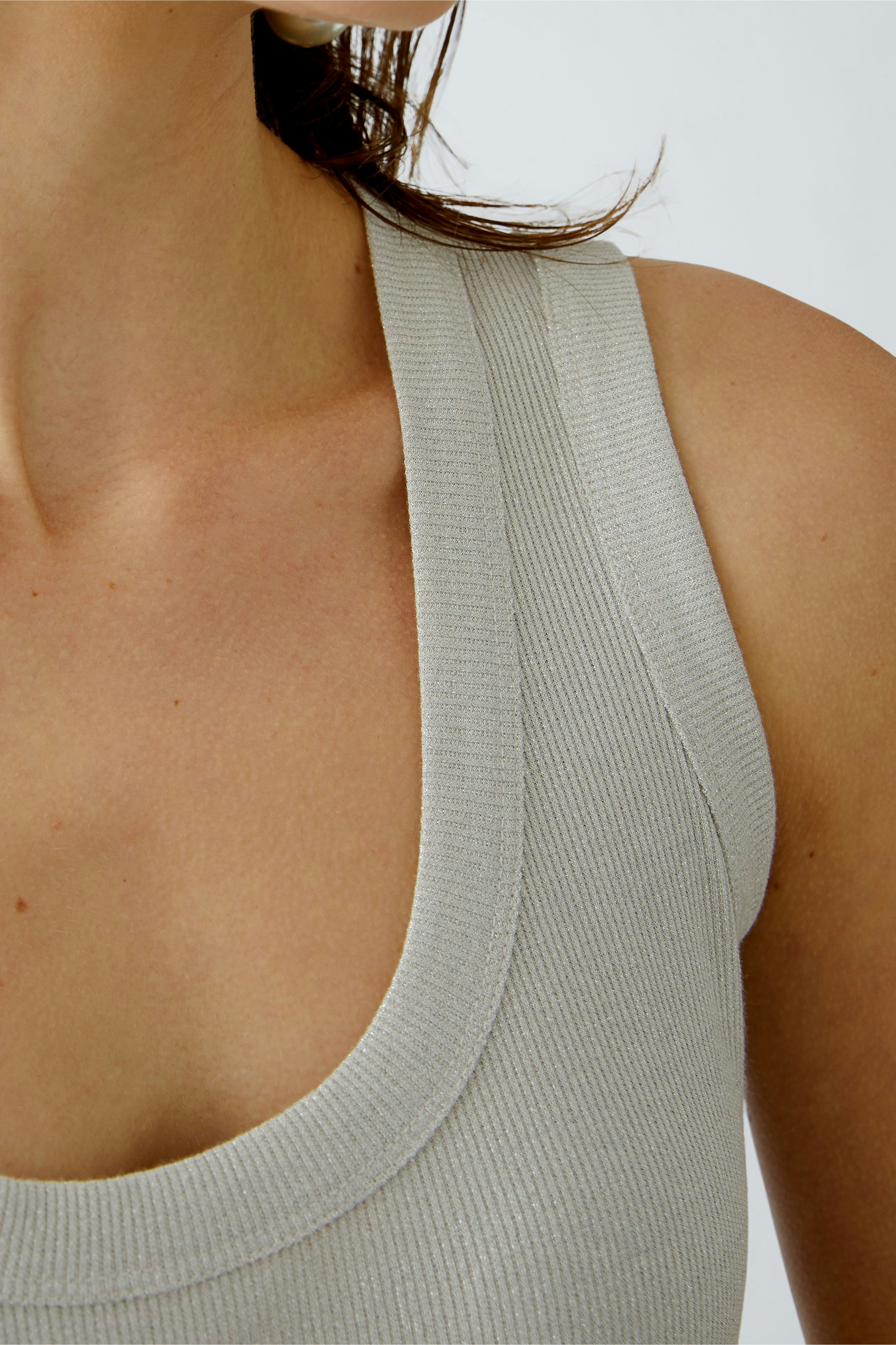 Stylish women's top: Close-up of a woman wearing a light gray ribbed tank top with a scoop neckline.