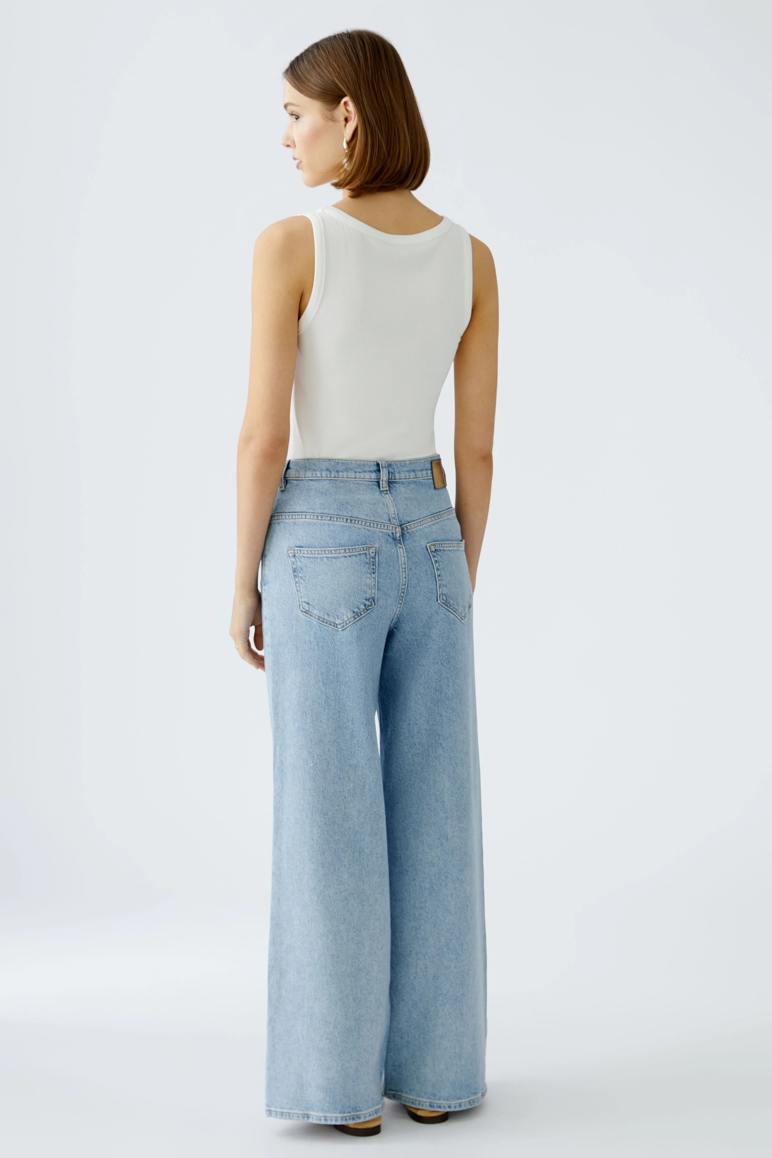 Stylish wide leg jeans: A woman in light blue wide leg jeans with a fitted white top.