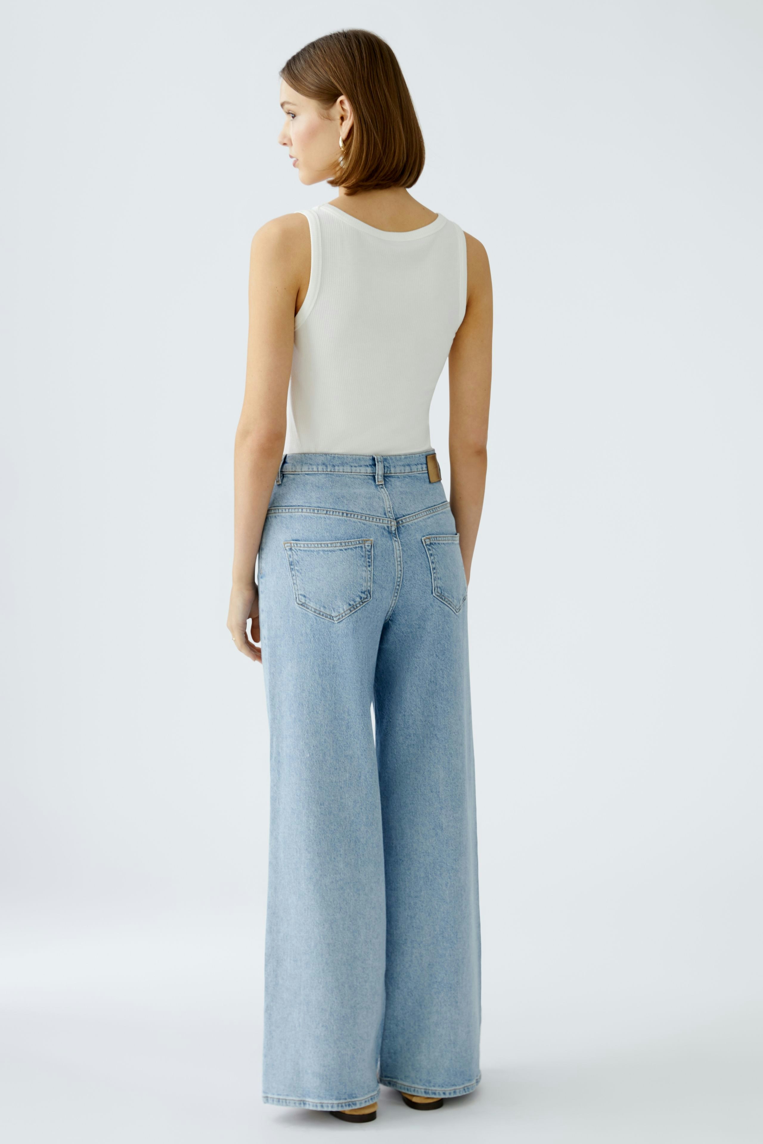 Stylish wide leg jeans: A woman in light blue wide leg jeans with a fitted white top.
