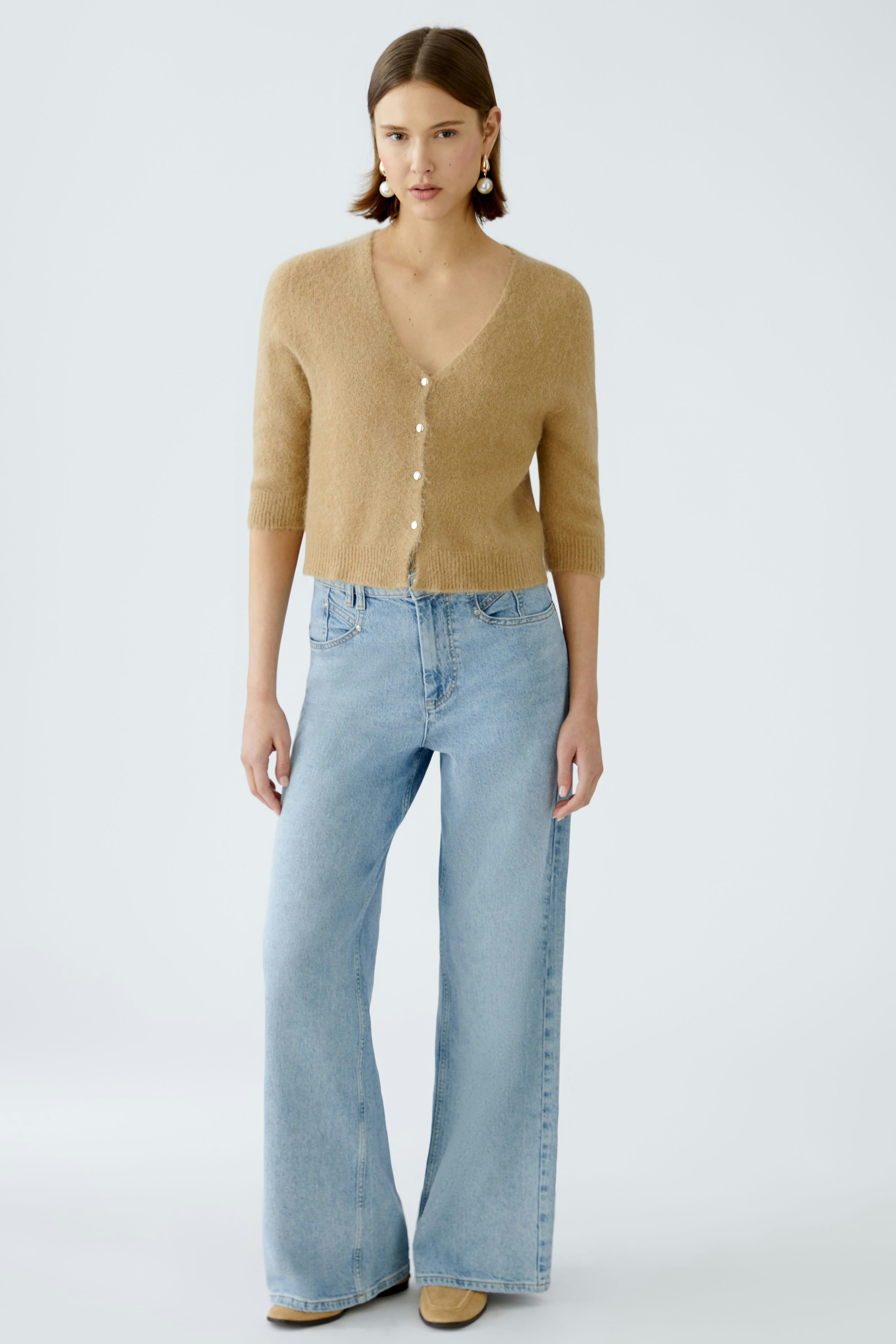 Stylish wide leg jeans: A woman in light blue wide leg jeans paired with a soft beige pullover.