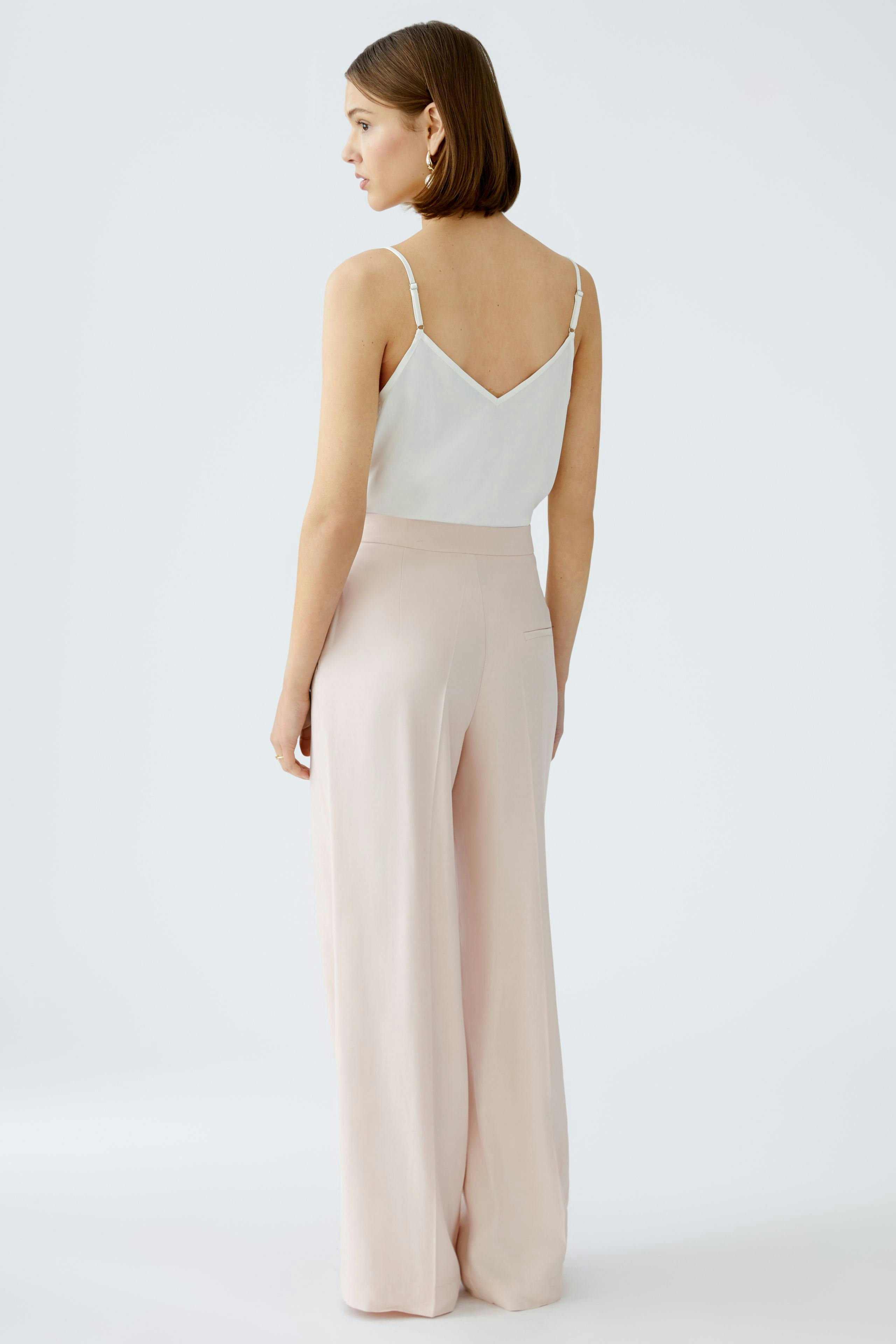 Elegant women's pleated trousers in soft pink, showcasing a stylish and relaxed fit.