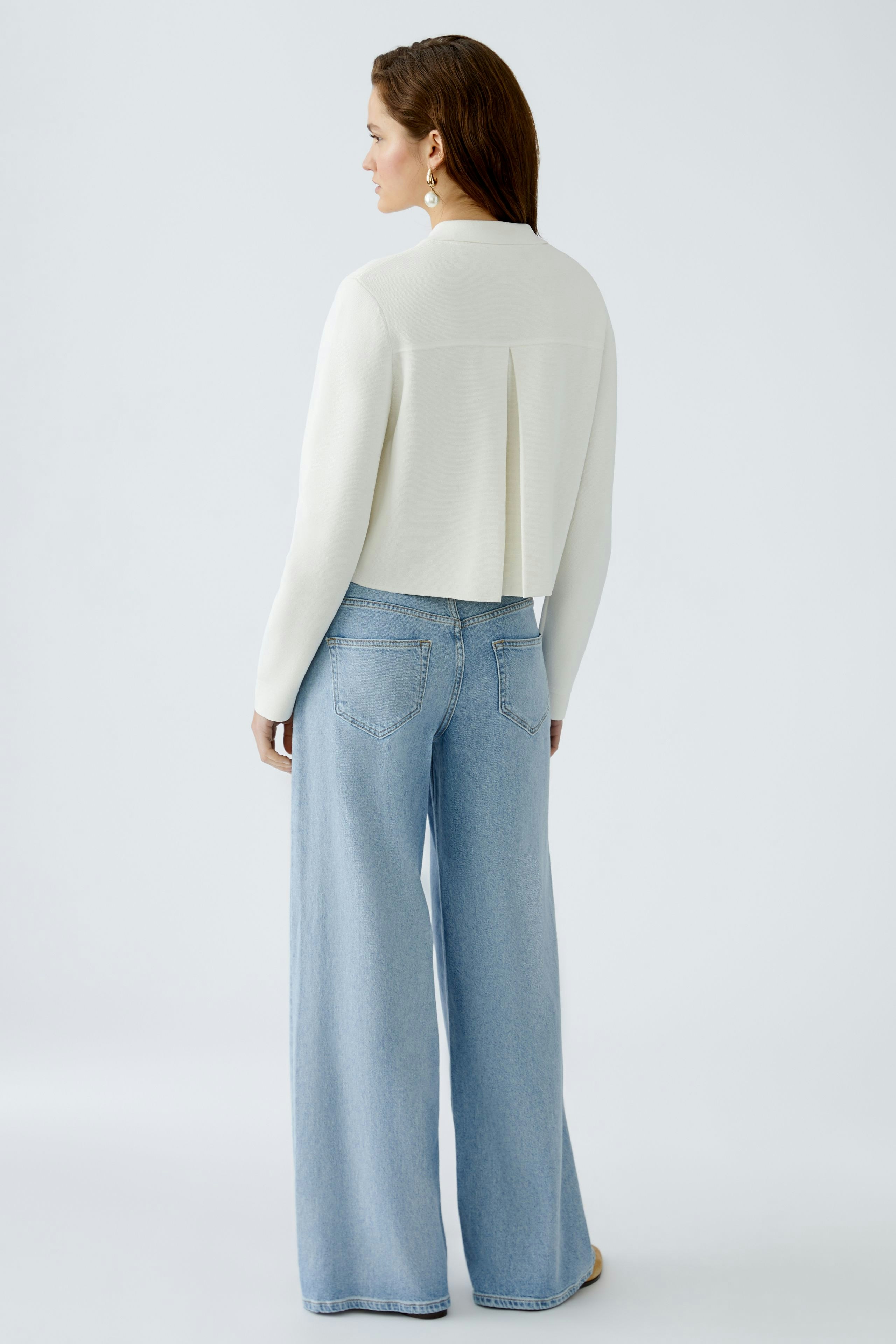 Stylish women's cardigan: A woman in a white cardigan paired with wide-leg jeans, showcasing a modern look.