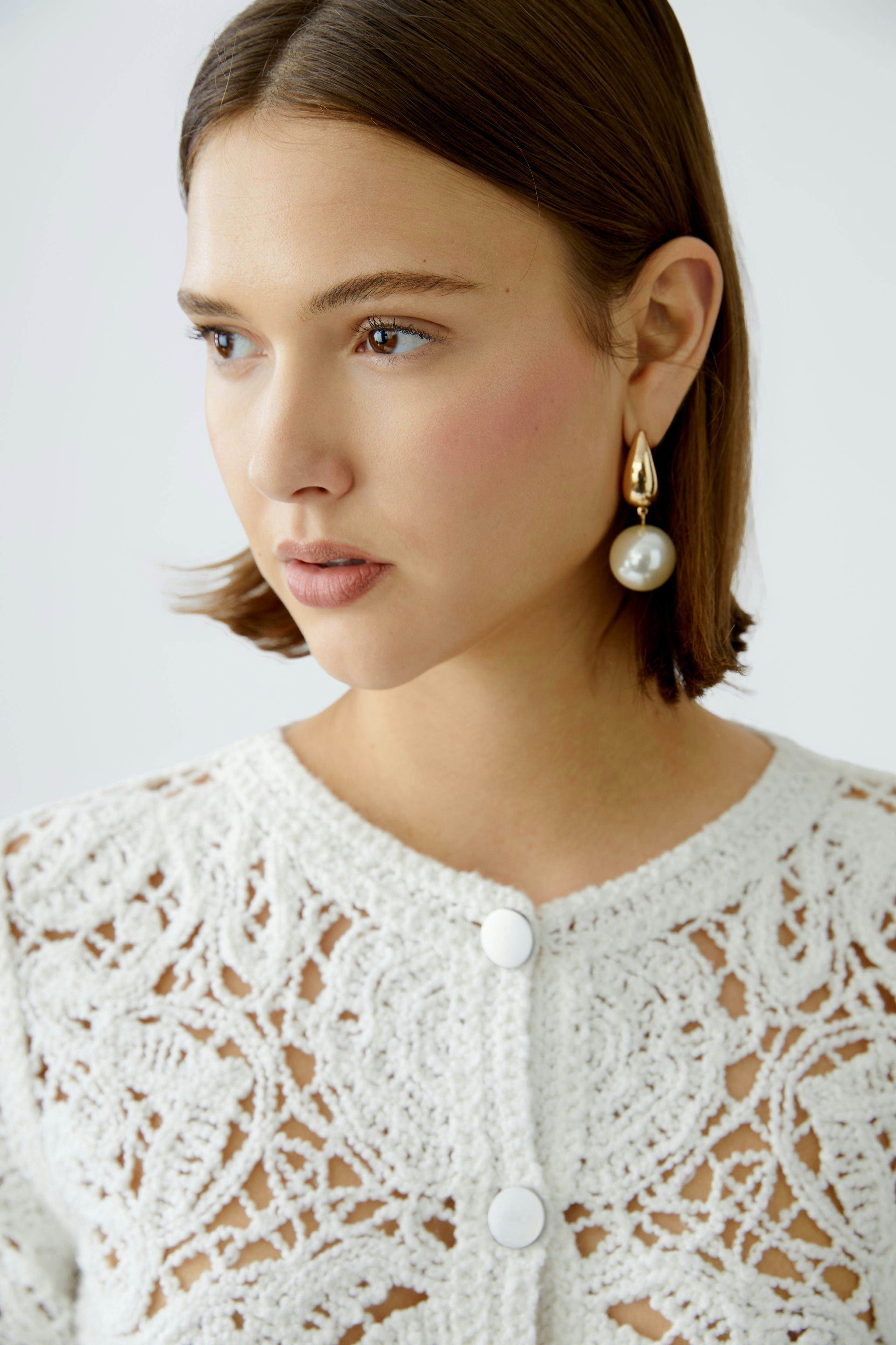 Elegant women's cardigan: Close-up of a woman wearing a delicate white knit cardigan with intricate patterns.