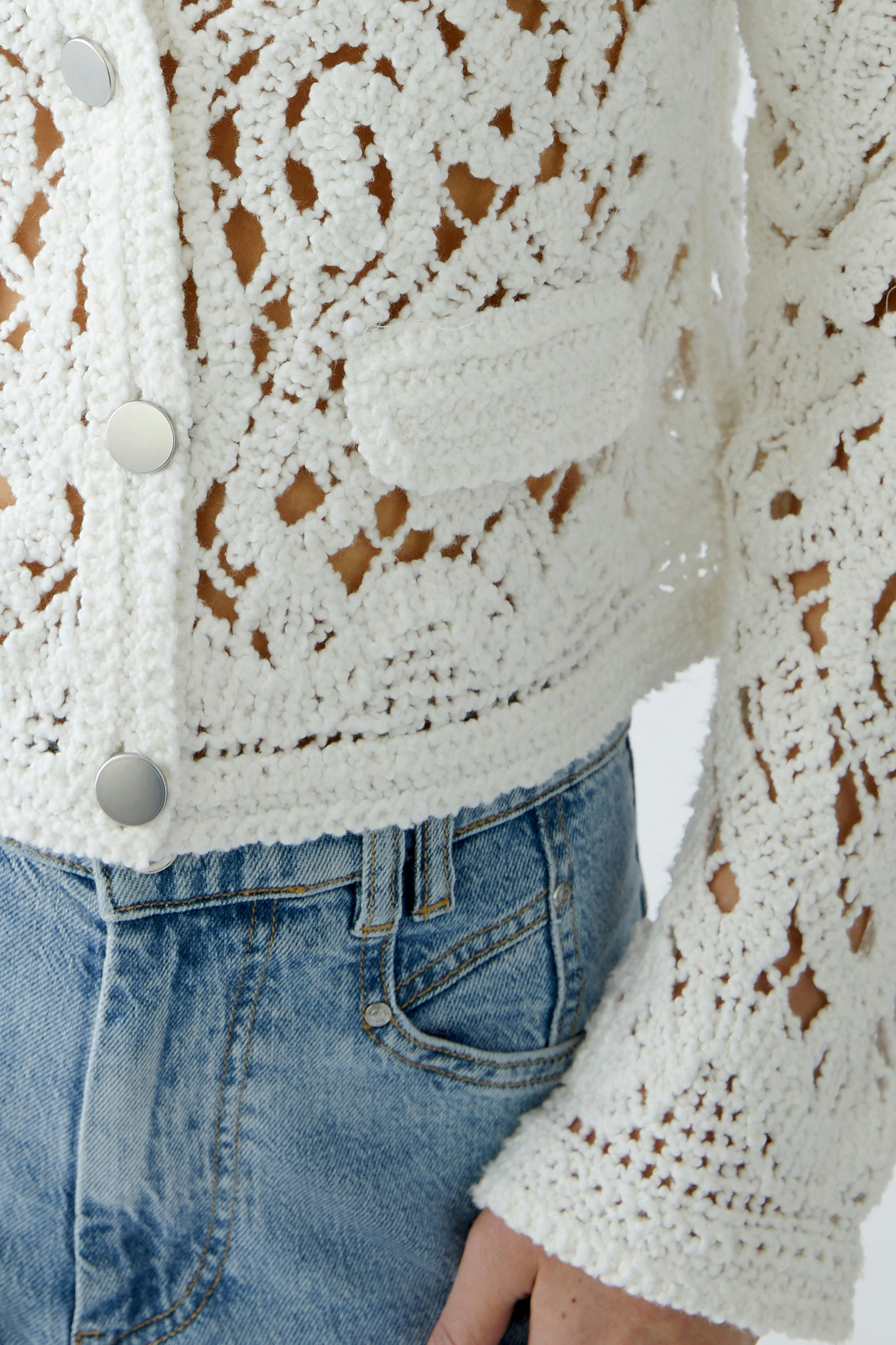 Stylish women's cardigan: A woman in a white crochet cardigan with a cropped fit and button details.