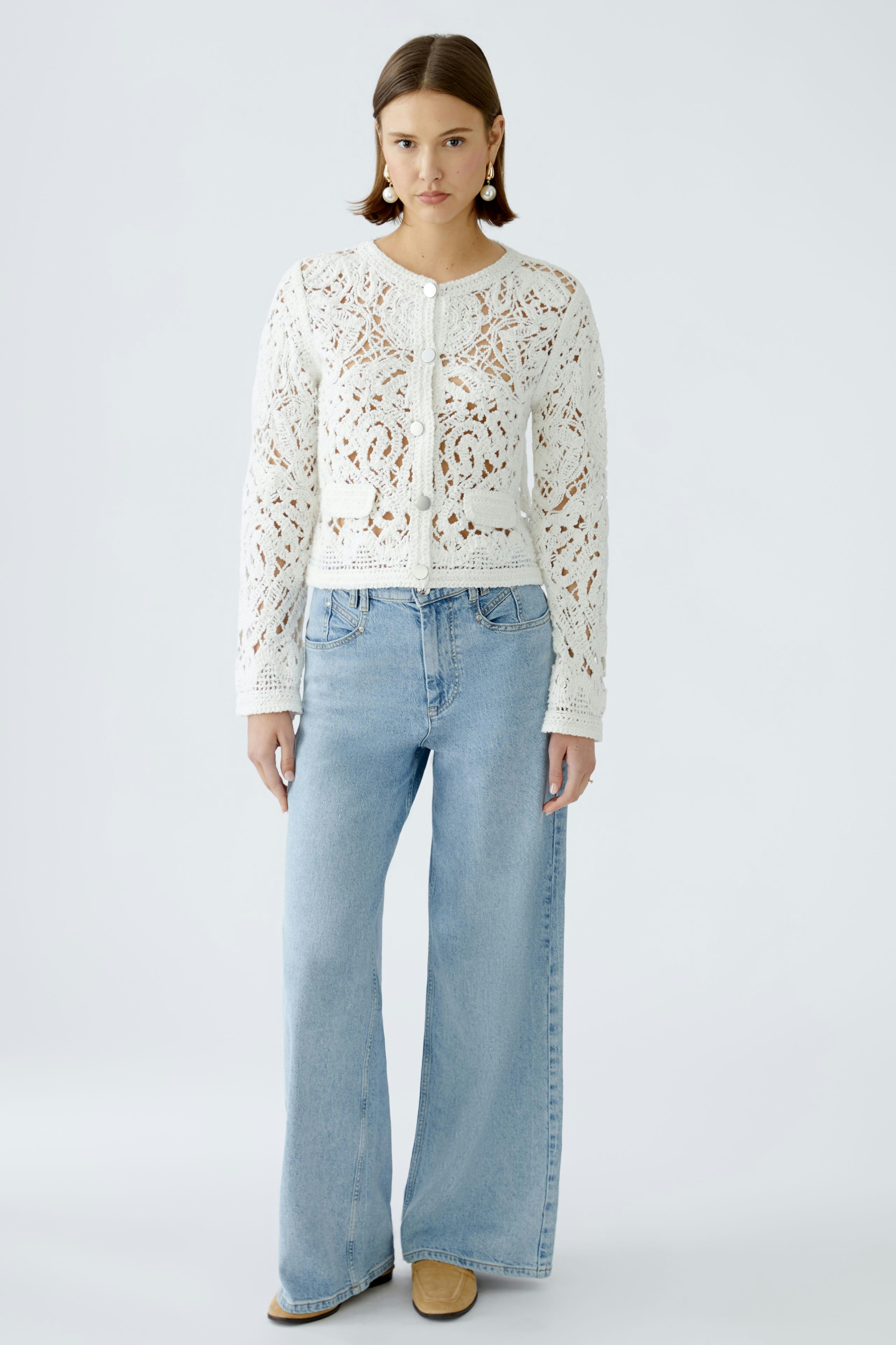 Stylish women's cardigan: A woman in a white knitted cardigan with intricate patterns and relaxed fit.