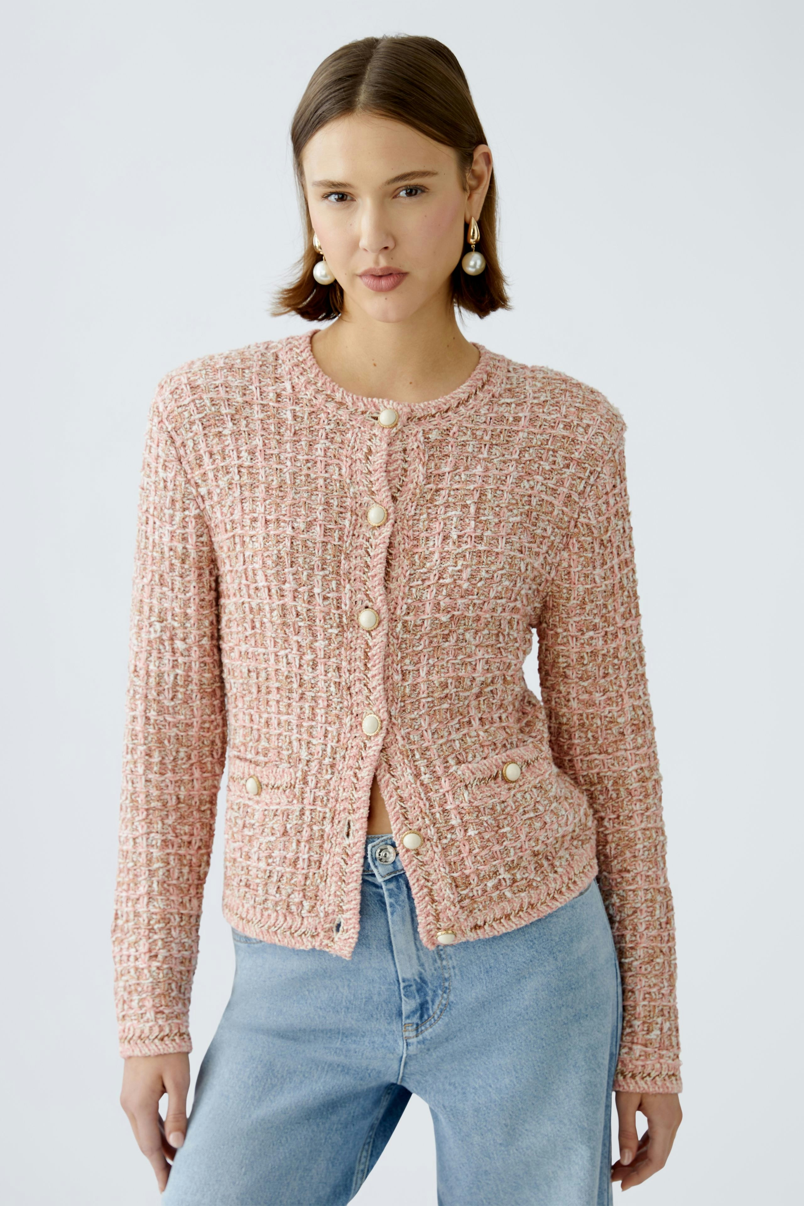 Stylish women's cardigan: A woman in a pink textured cardigan with buttons and casual jeans.