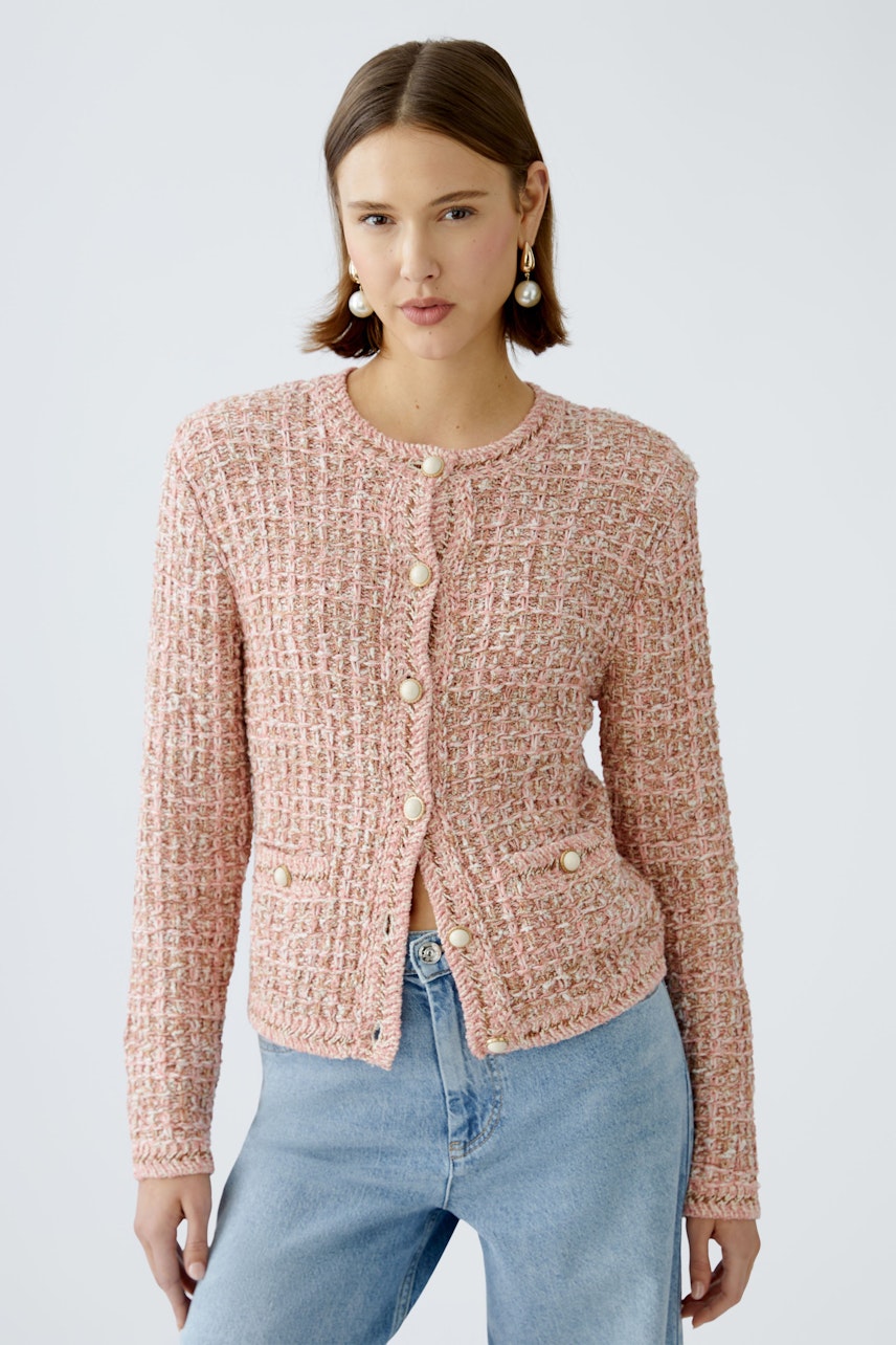 Stylish women's cardigan: A woman in a pink textured cardigan with buttons and casual jeans.