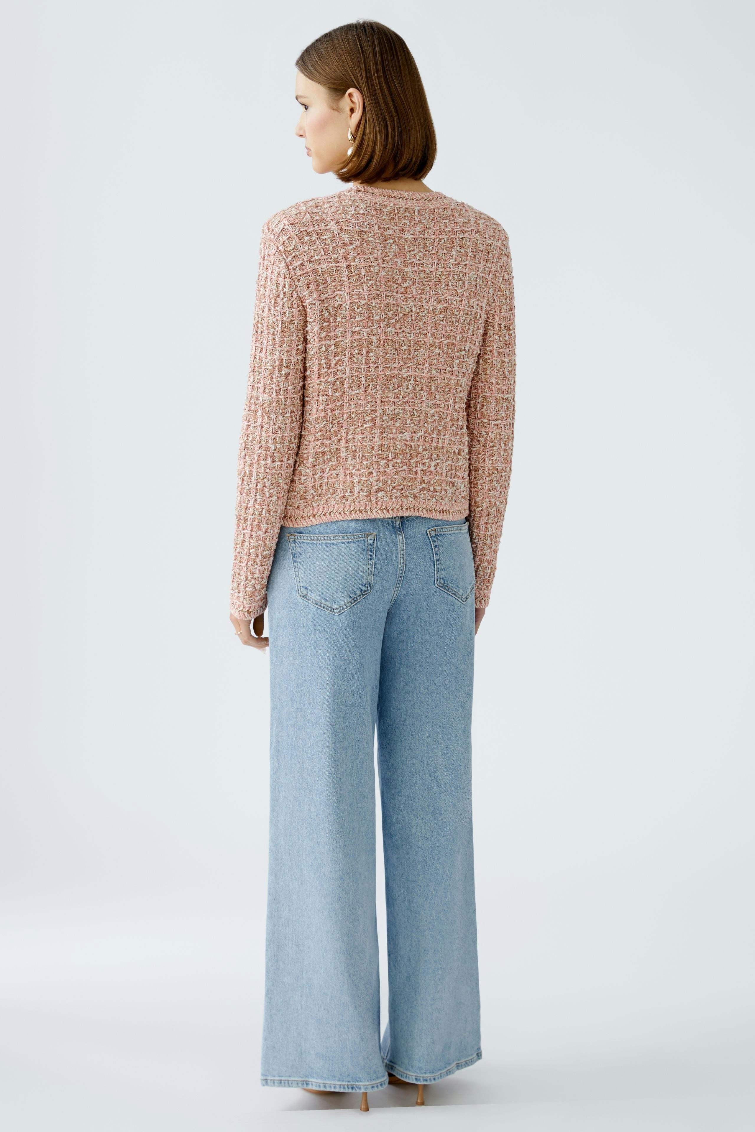 Stylish women's cardigan: A woman in a textured pink cardigan paired with wide-leg jeans.