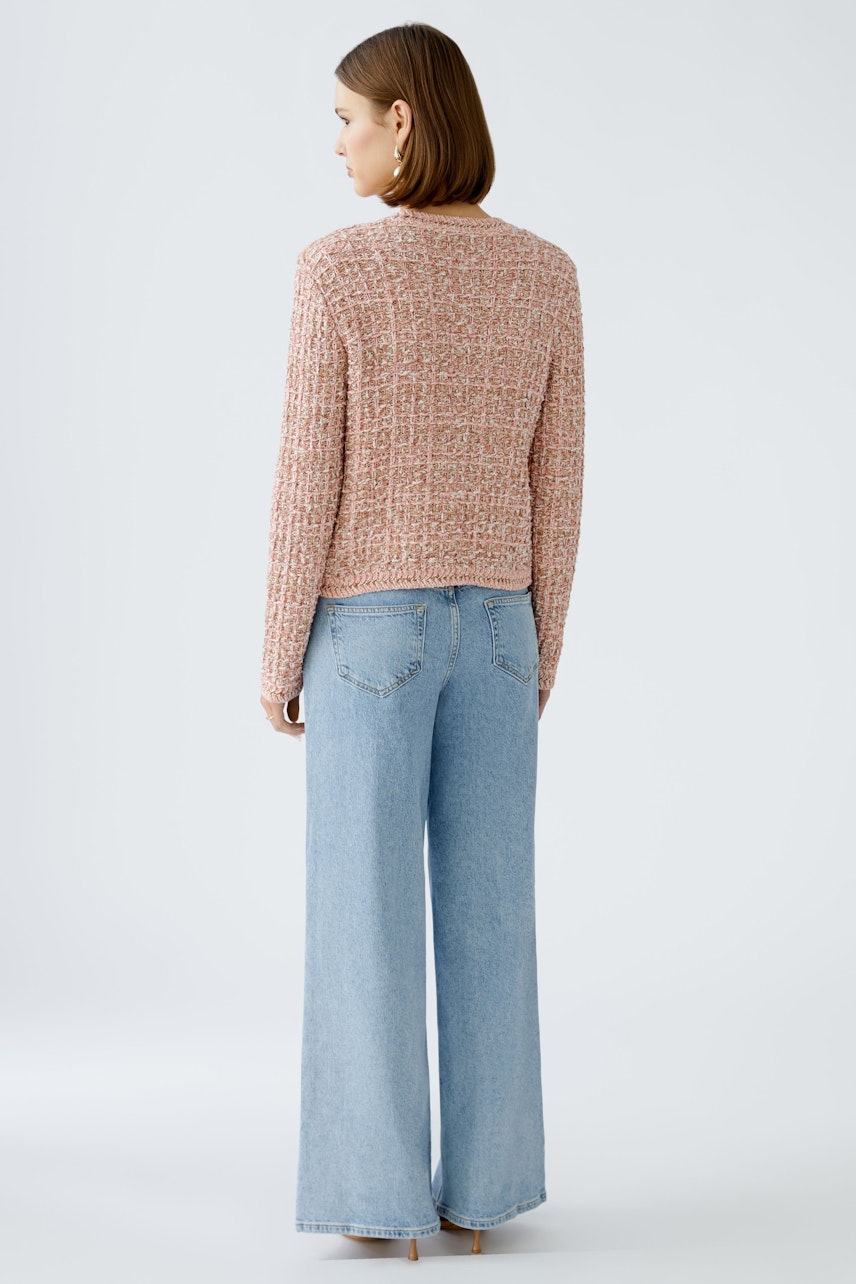 Stylish women's cardigan: A woman in a textured pink cardigan paired with wide-leg jeans.