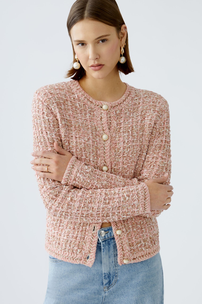 Stylish women's cardigan: A woman in a pink textured cardigan with buttons, paired with a denim skirt.