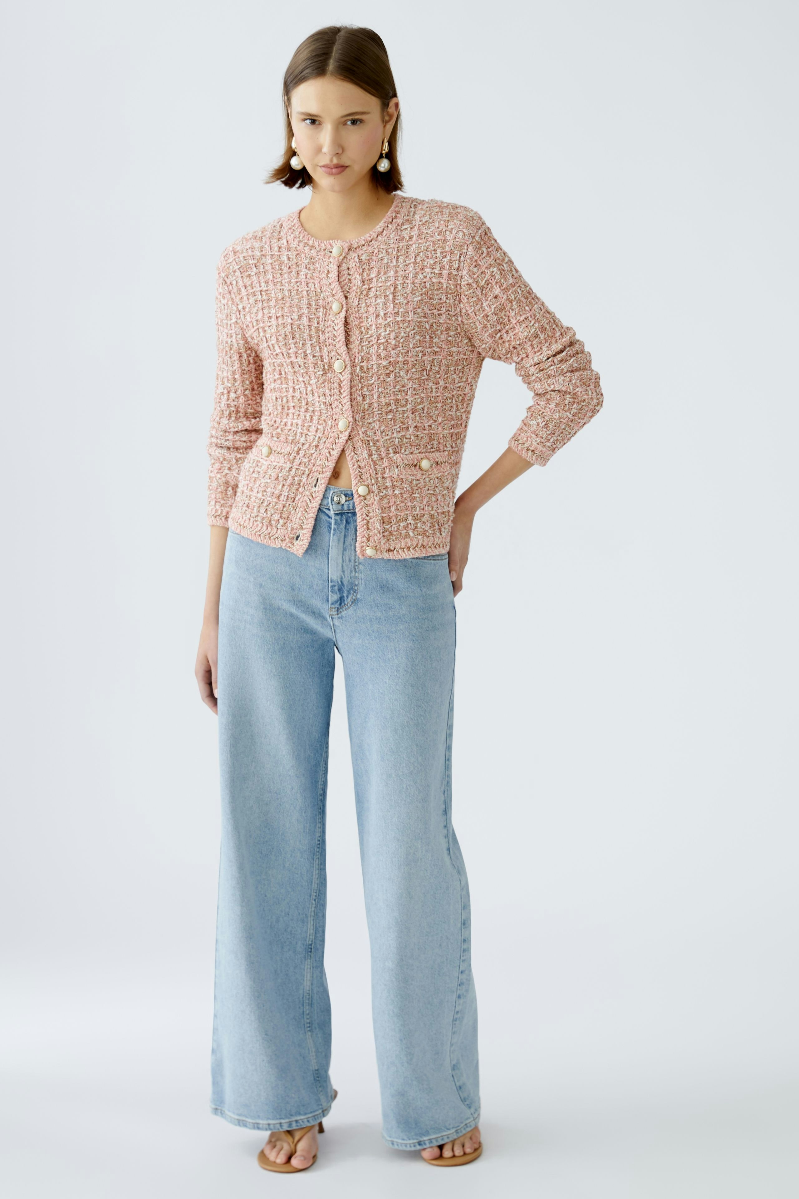 Stylish women's cardigan: A woman in a pink textured cardigan with buttons, paired with wide-leg jeans.
