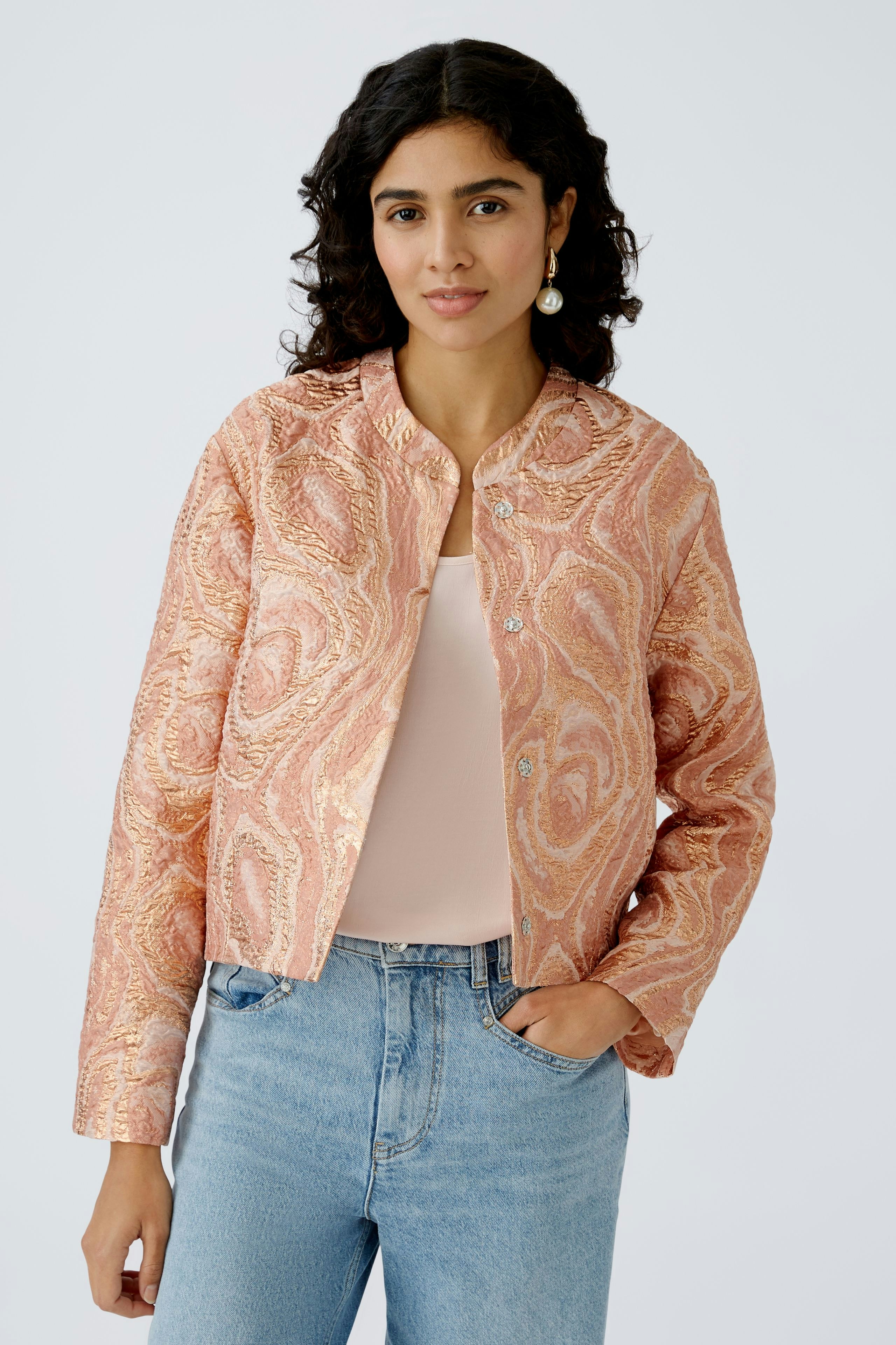 Stylish women's jacket: A woman in a pink patterned jacket paired with a simple top and jeans.