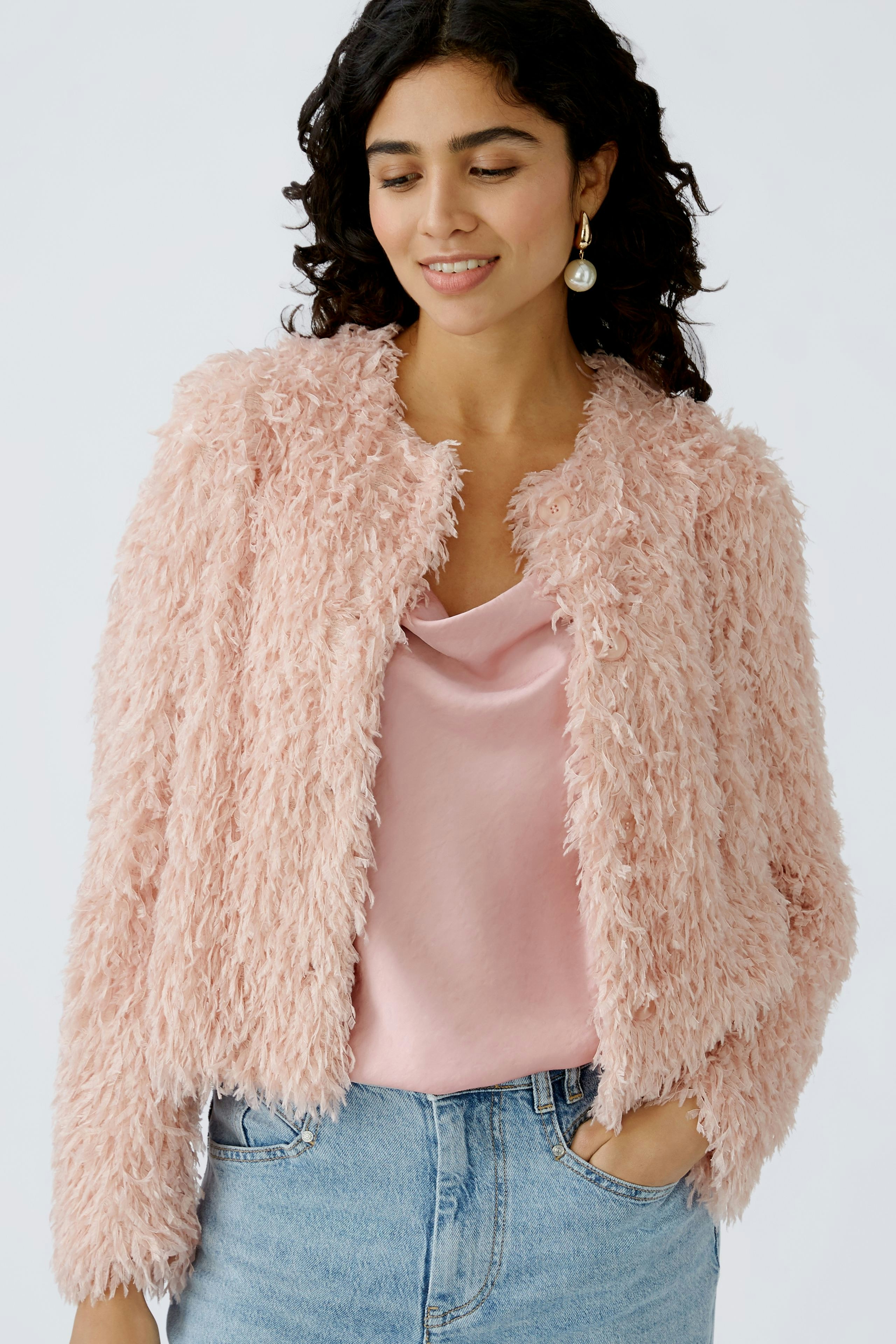 Stylish women's jacket: A woman in a fluffy pink jacket over a satin top, exuding elegance.