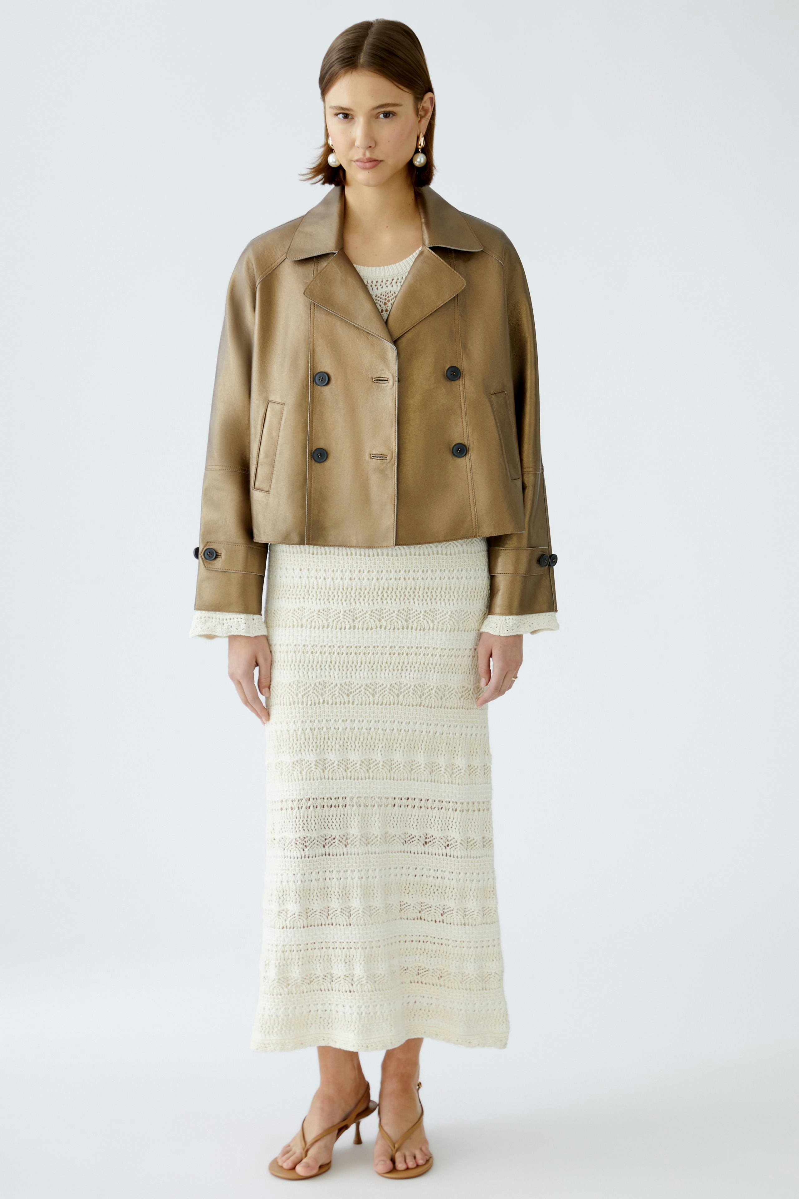 Stylish women's leather jacket: A woman in a cropped brown leather jacket over a white dress.