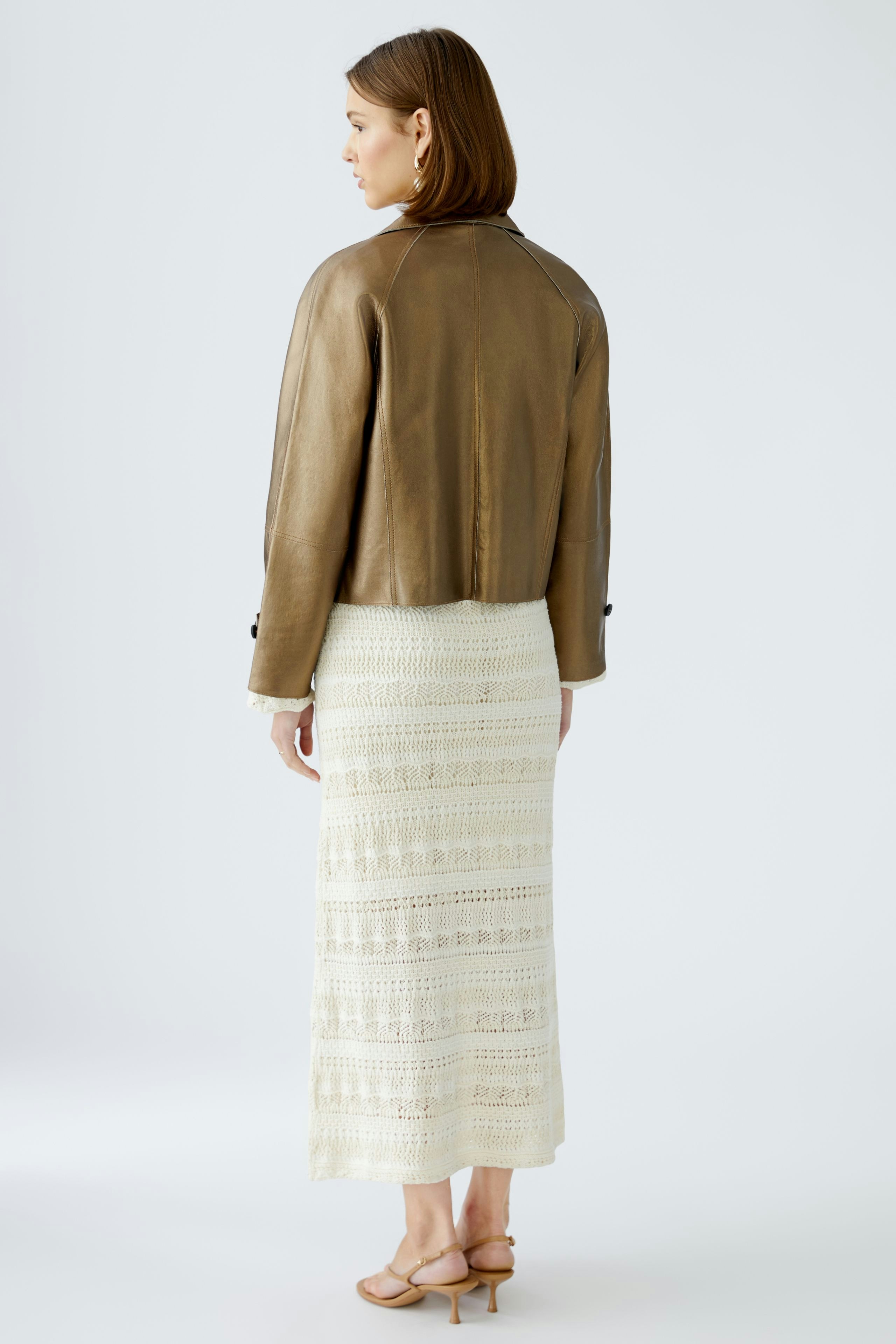 Stylish women's leather jacket: A woman in a chic brown leather jacket paired with a long white skirt.