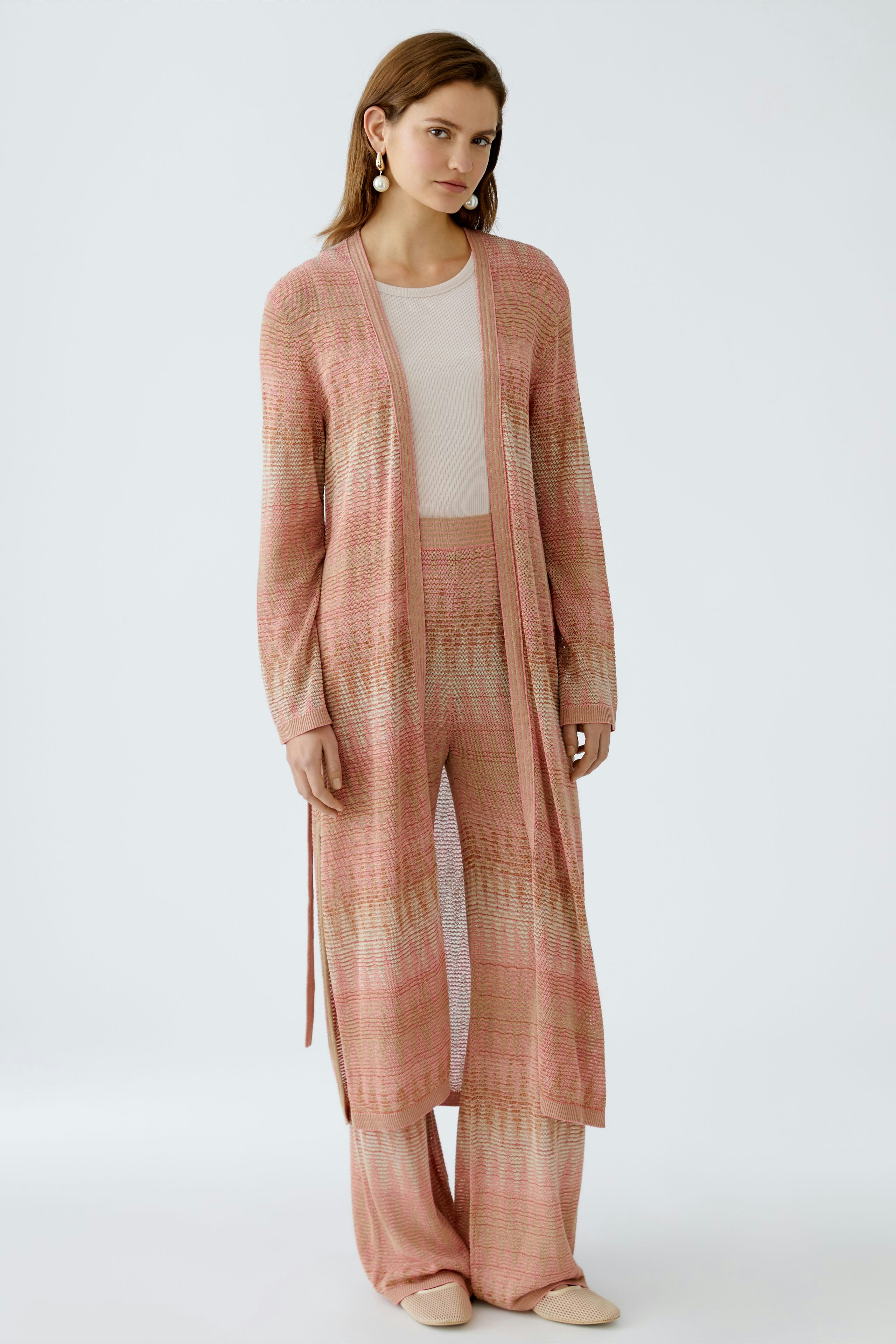 Stylish women's cardigan: A woman in a pink knitted cardigan paired with matching pants.