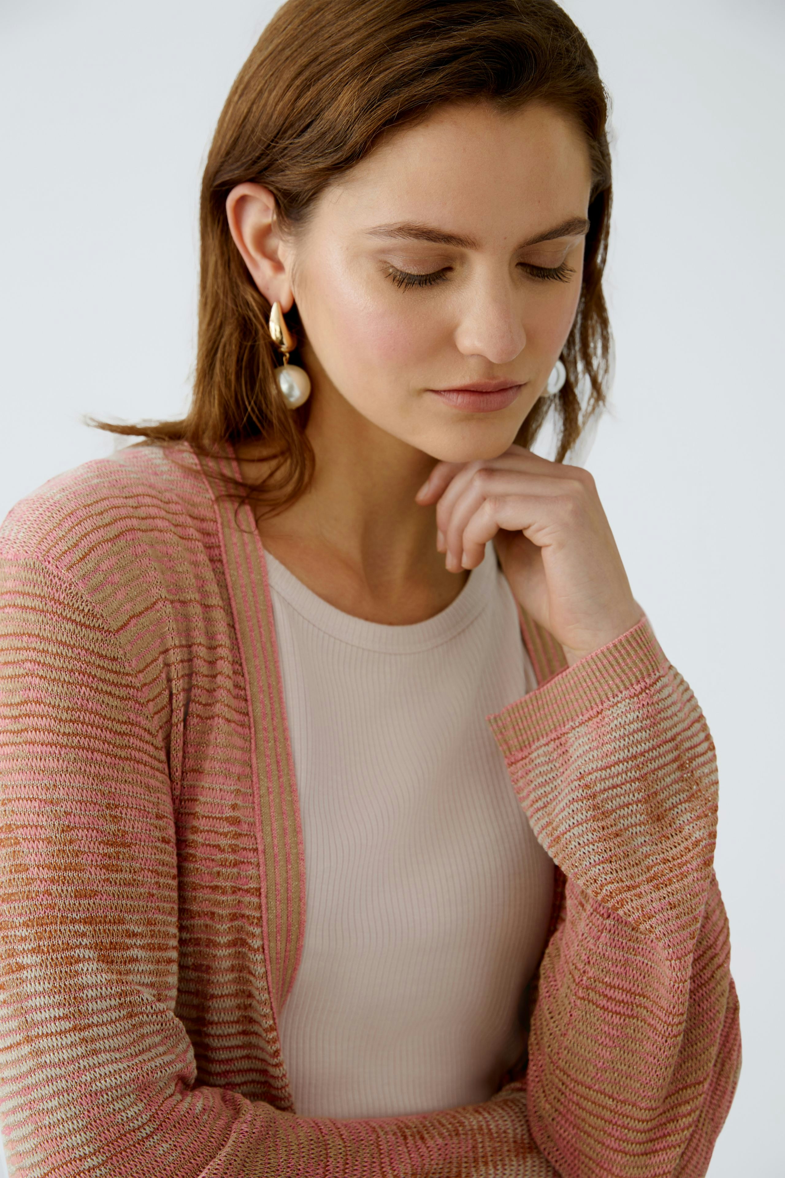 Stylish women's cardigan: A woman in a pink striped cardigan over a light top, exuding elegance.