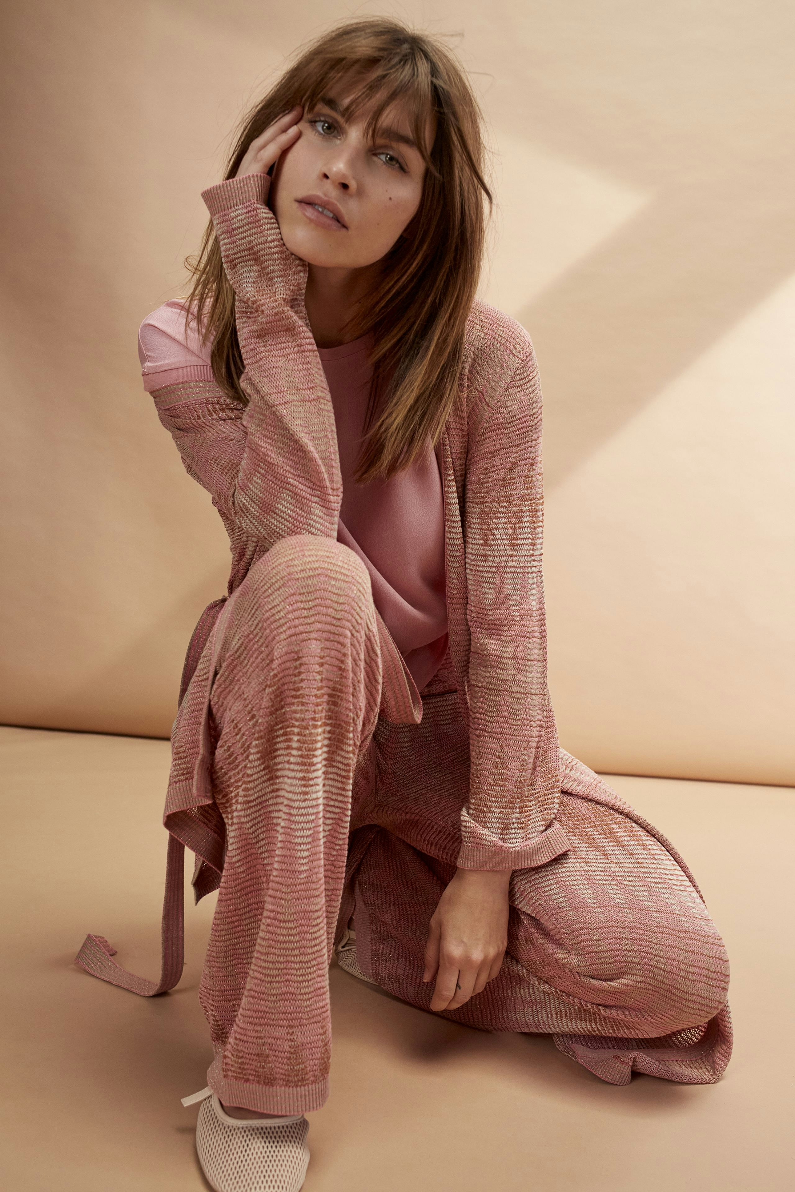 Stylish women's cardigan: A woman in a pink knitted cardigan with a relaxed fit, exuding comfort.