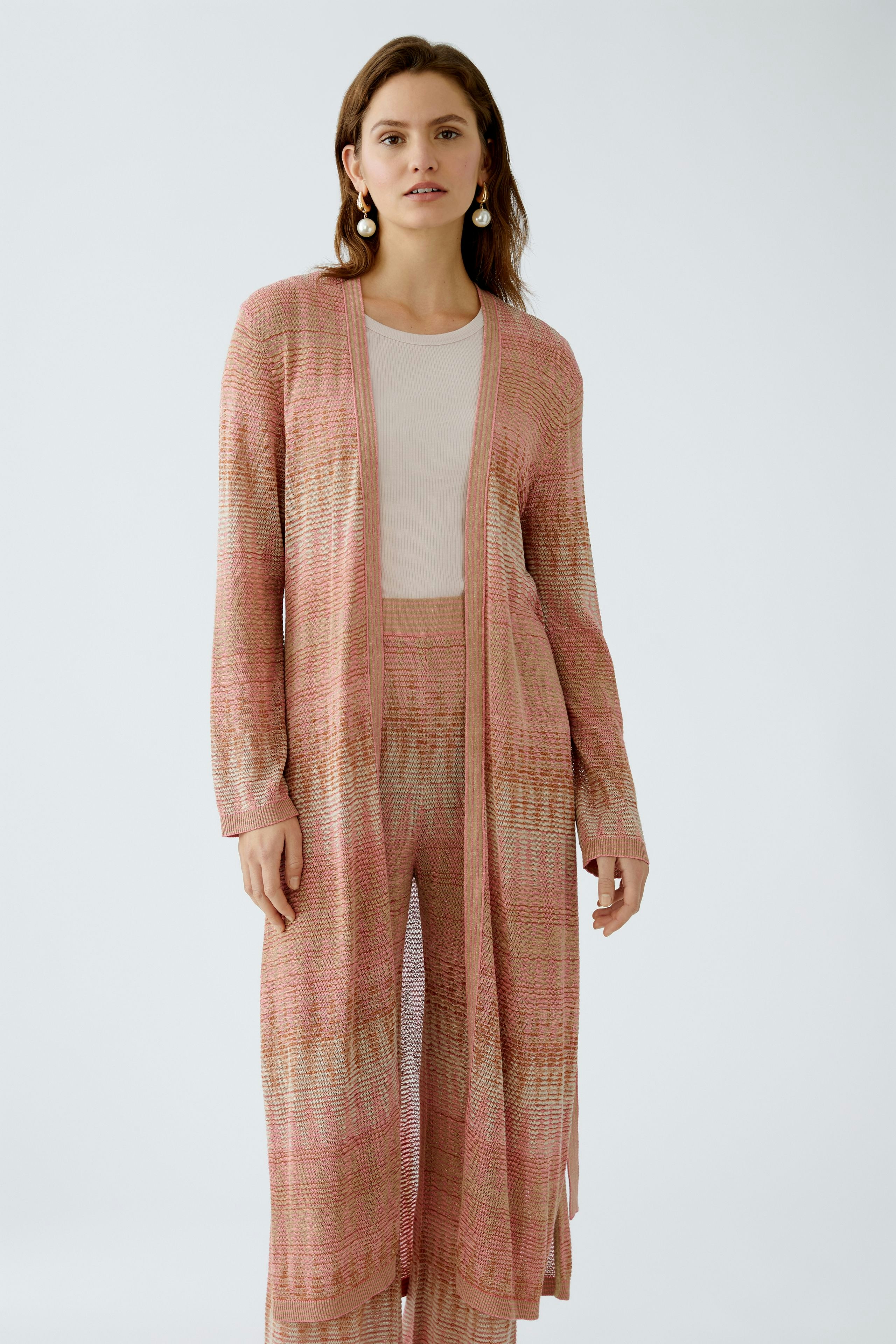 Stylish women's cardigan: A woman in a pink knitted cardigan over a matching outfit, exuding elegance.