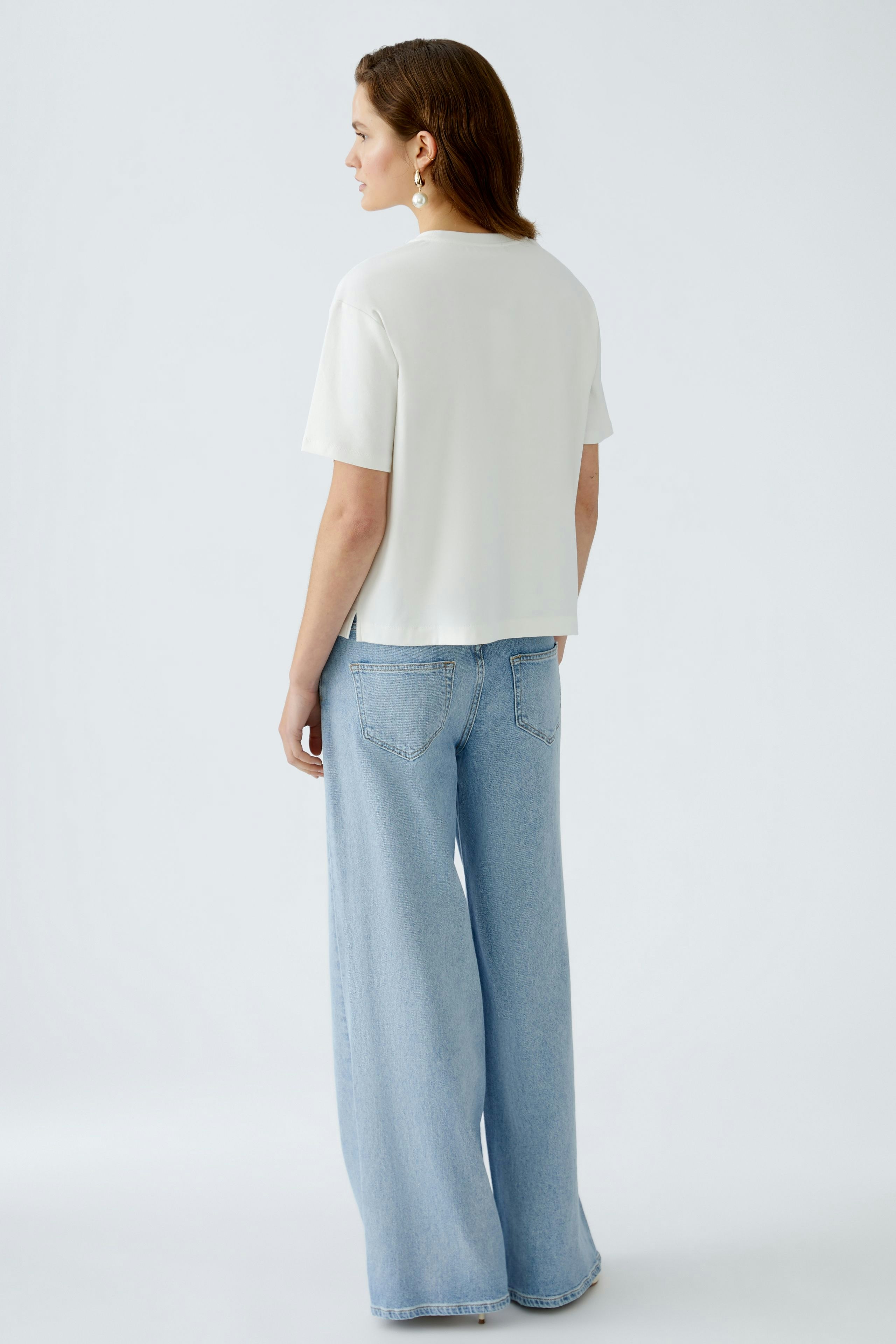 Stylish women's T-shirt: A woman in a white T-shirt and wide jeans, showcasing a modern look.