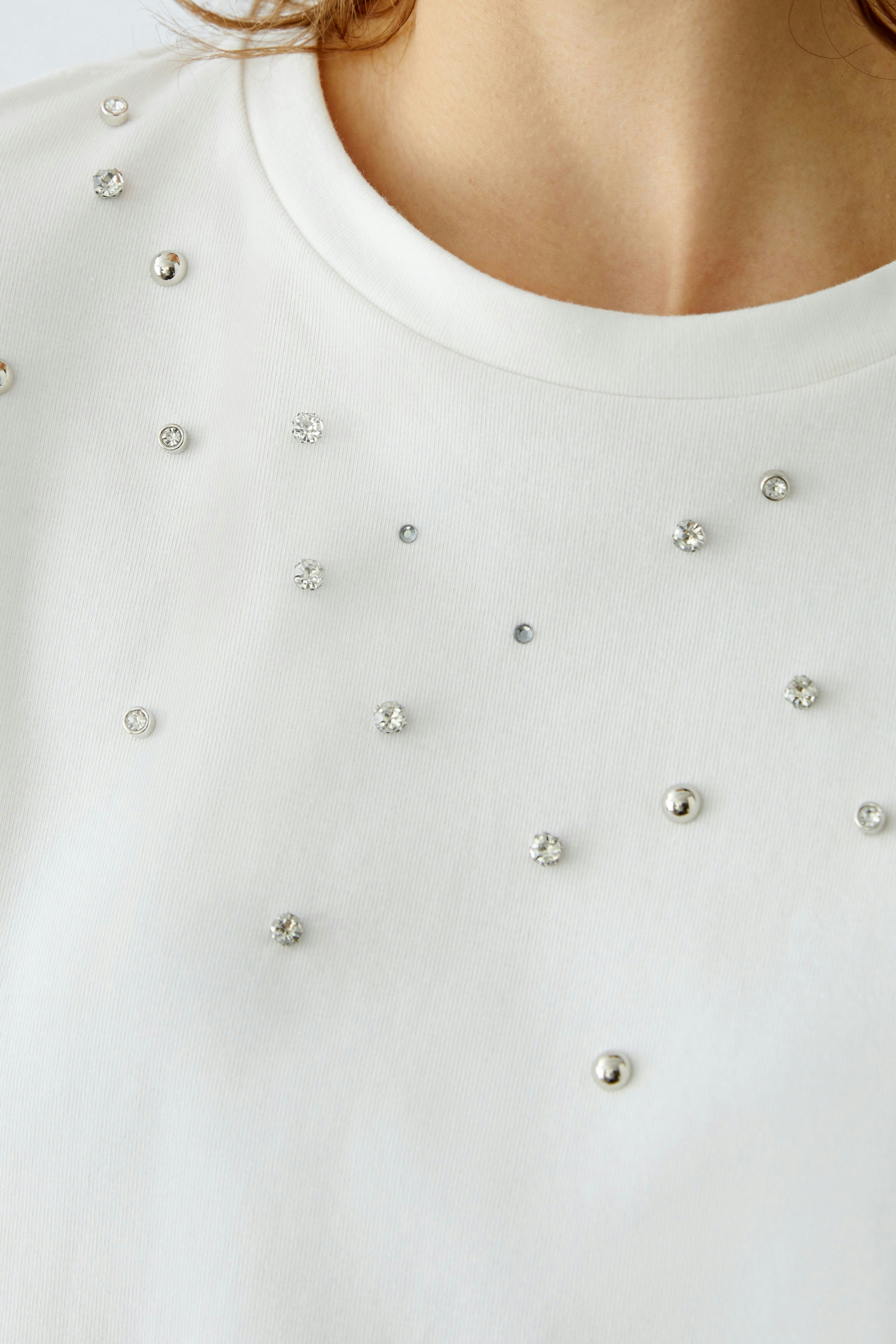 Elegant women's T-shirt with decorative embellishments, perfect for casual or dressy occasions.