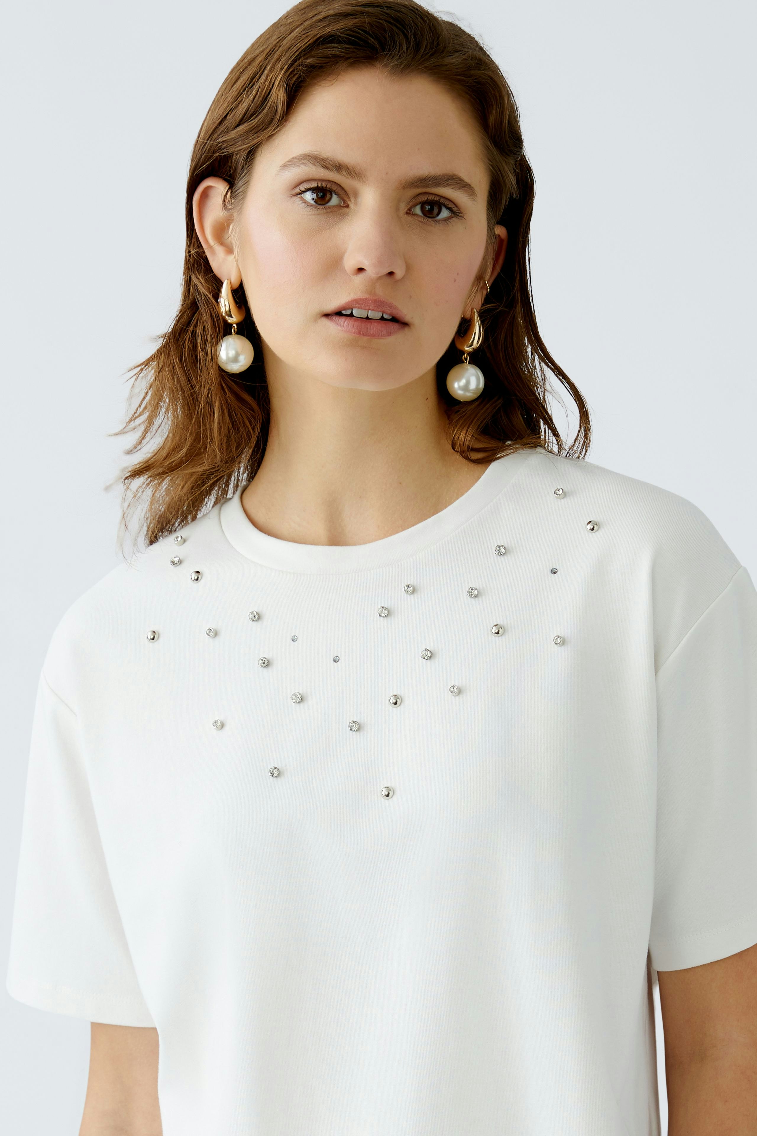 Stylish women's T-shirt: A woman in a white tee adorned with sparkling embellishments.