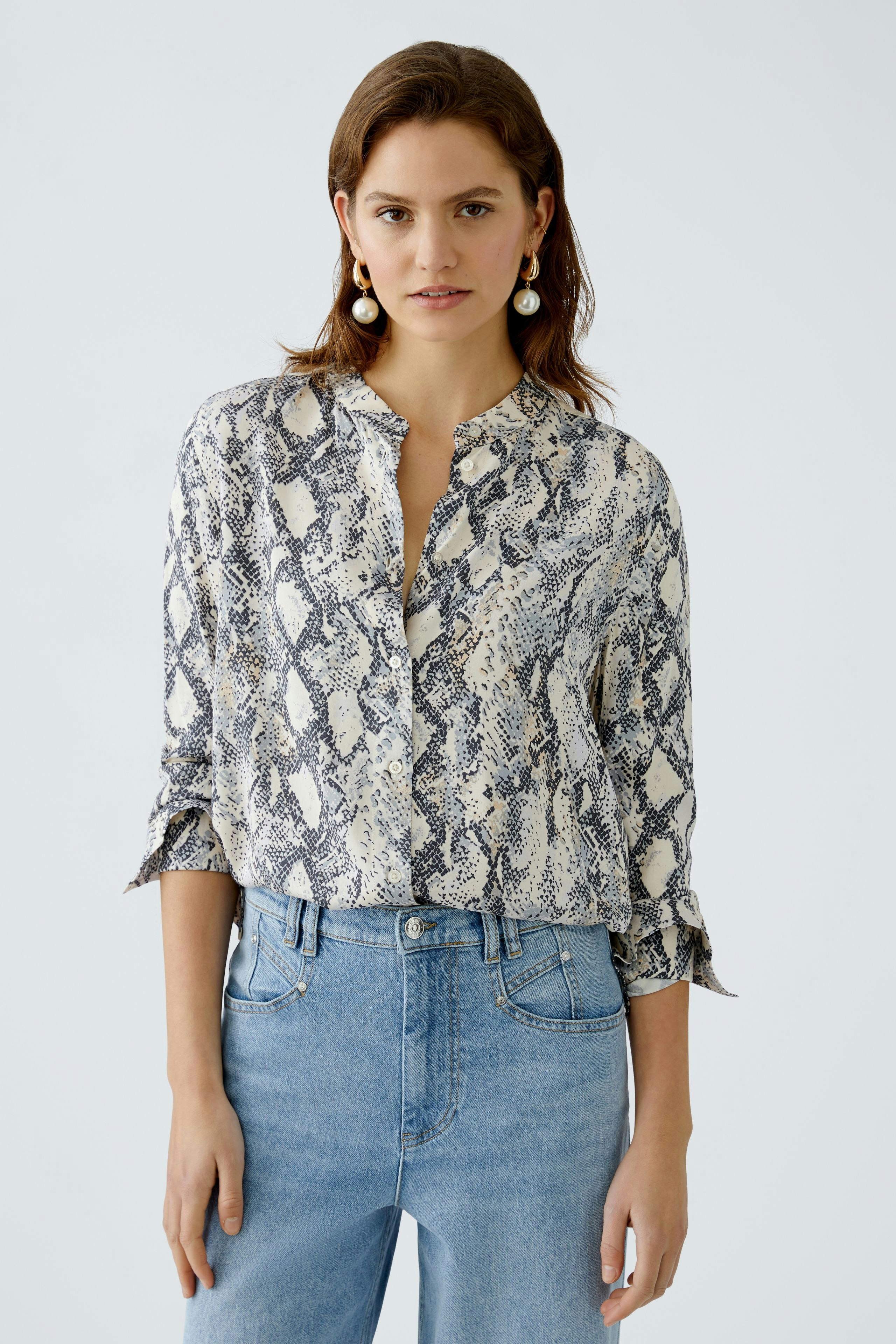 Elegante Damen-Bluse im Schlangenprint, lässig kombiniert mit Jeans, präsentiert von einer Frau.