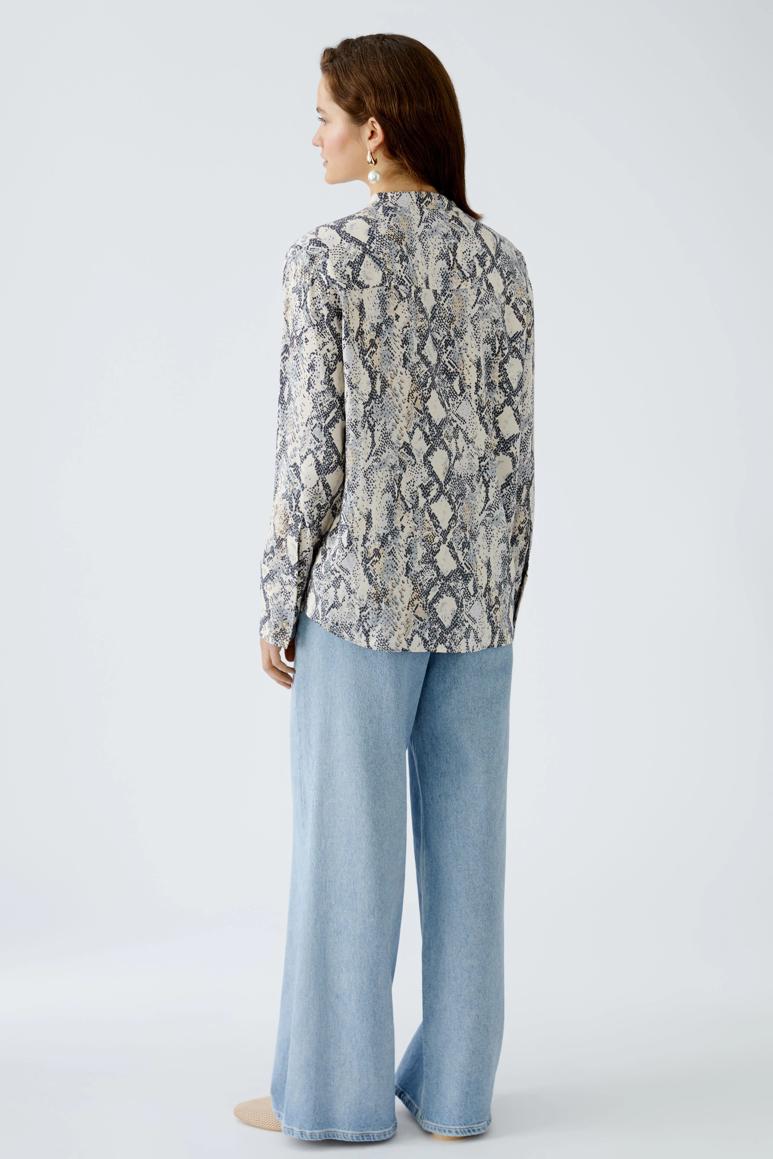 Elegante Damen-Bluse mit Schlangenmuster, lässig kombiniert mit weiten Jeans.