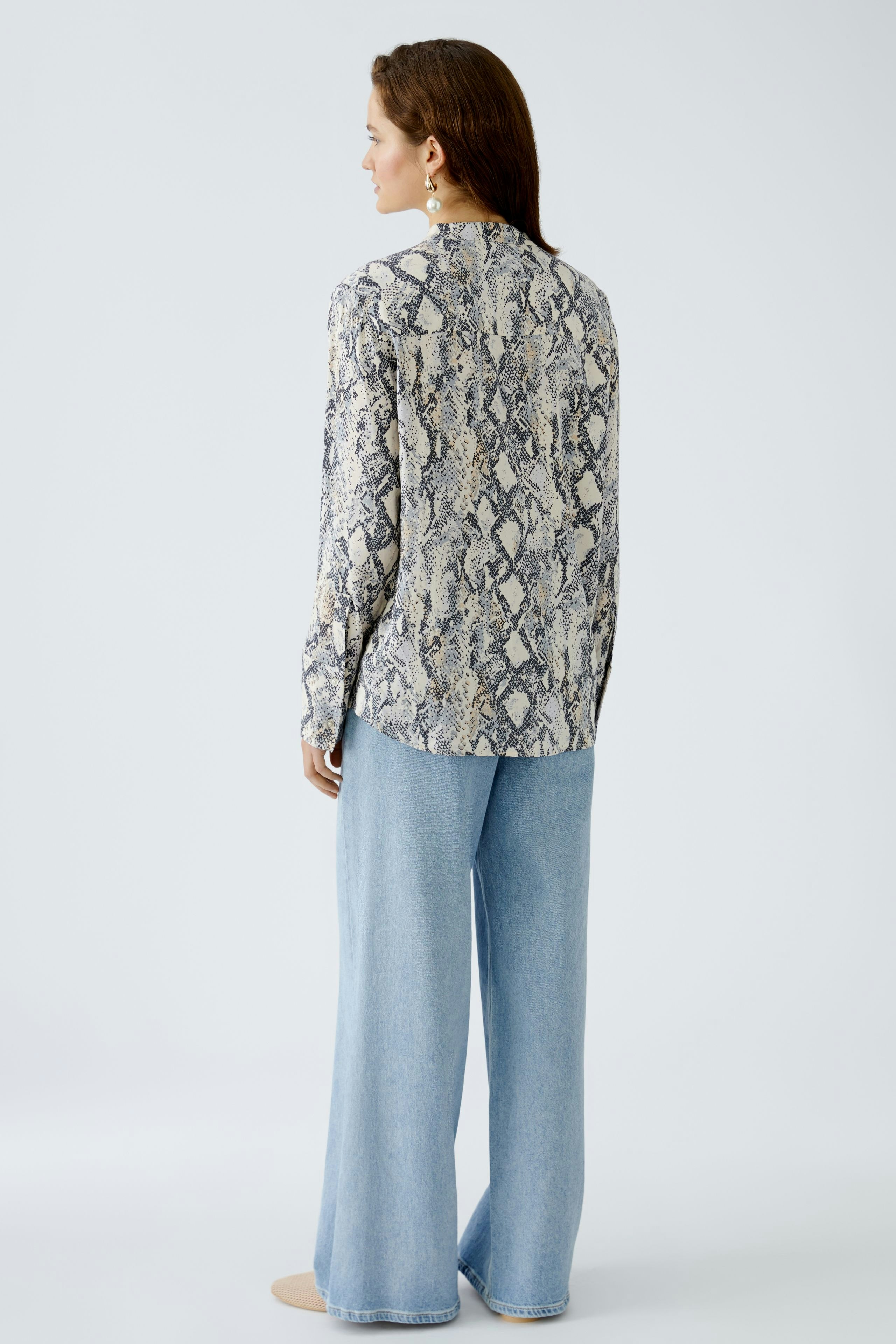 Elegante Damen-Bluse mit Schlangenmuster, lässig kombiniert mit weiten Jeans.