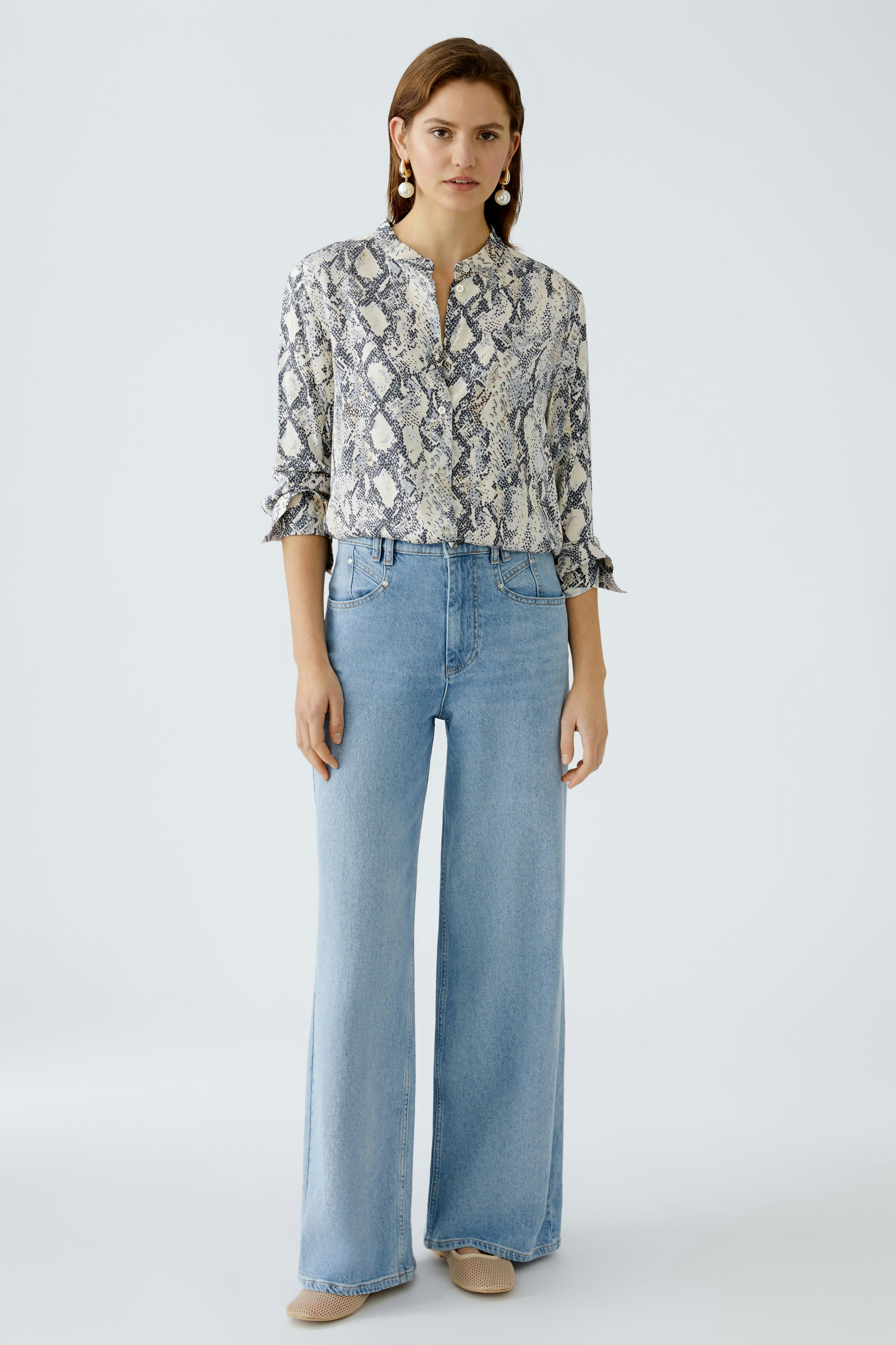 Moderne Damen-Bluse: Frau in schicker Bluse mit Schlangenmuster und lässigen Jeans.