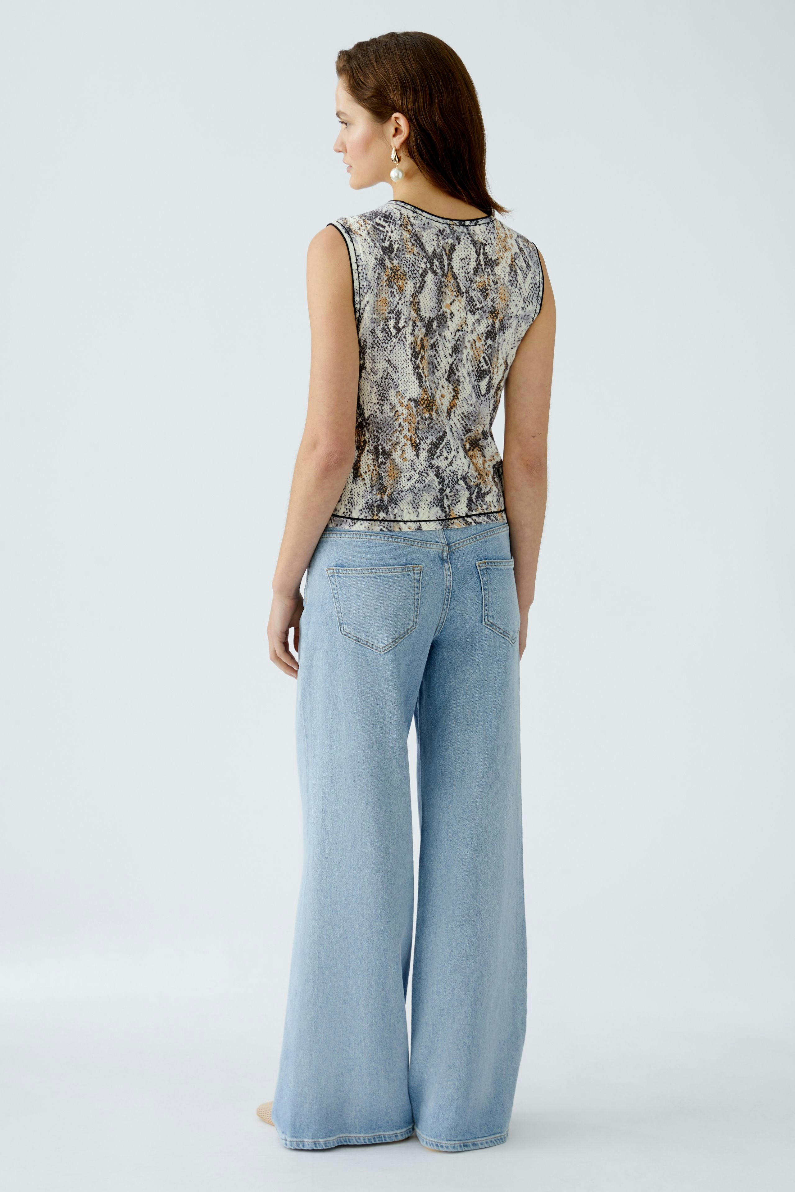 Elegantes Damen-Top: Frau trägt ein schlangenmuster Top mit lässigen Jeans und langen Beinen.