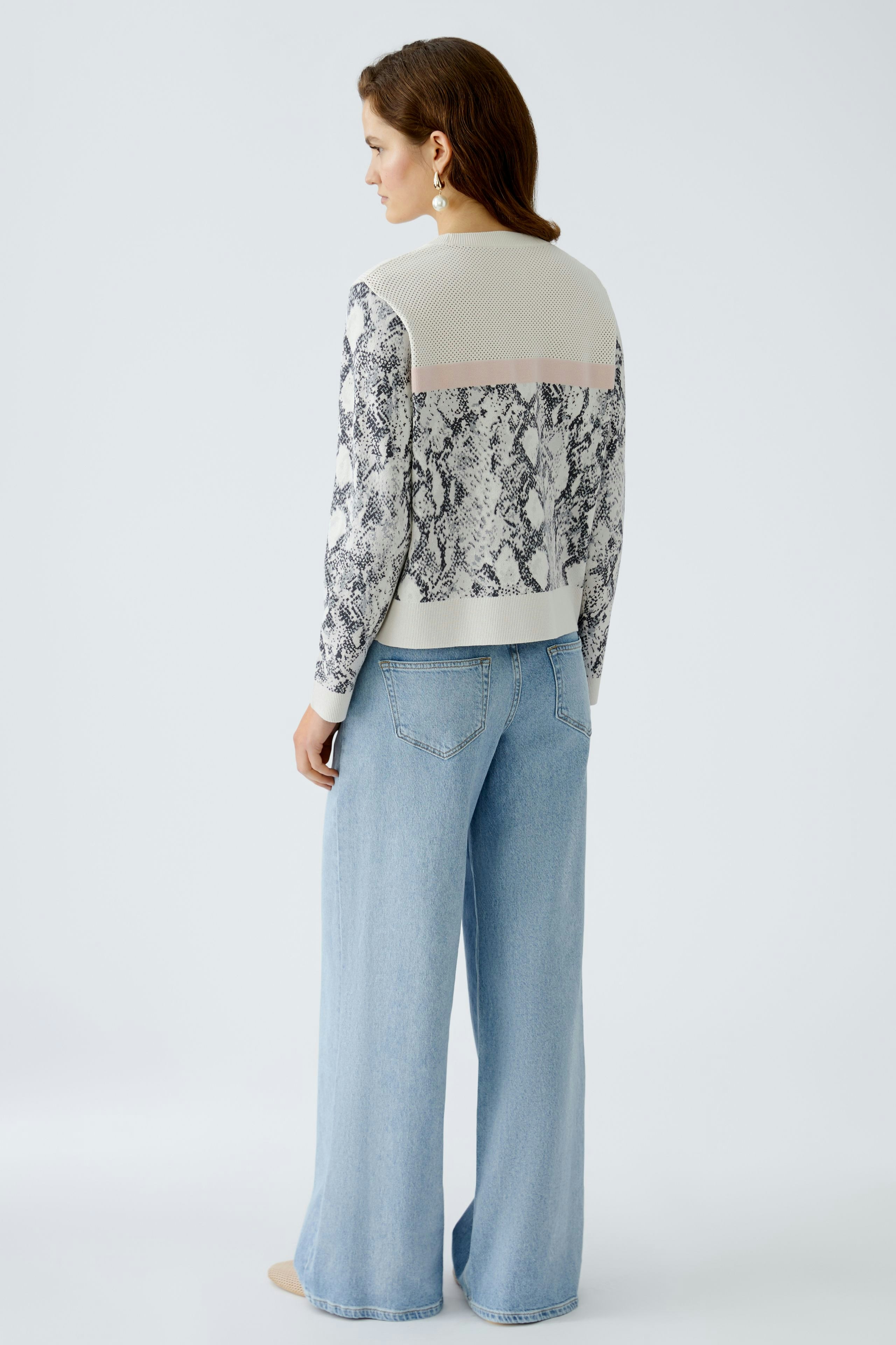 Damen-Pullover: Frau mit schickem, gemustertem Pullover und lässigen Jeans von hinten.