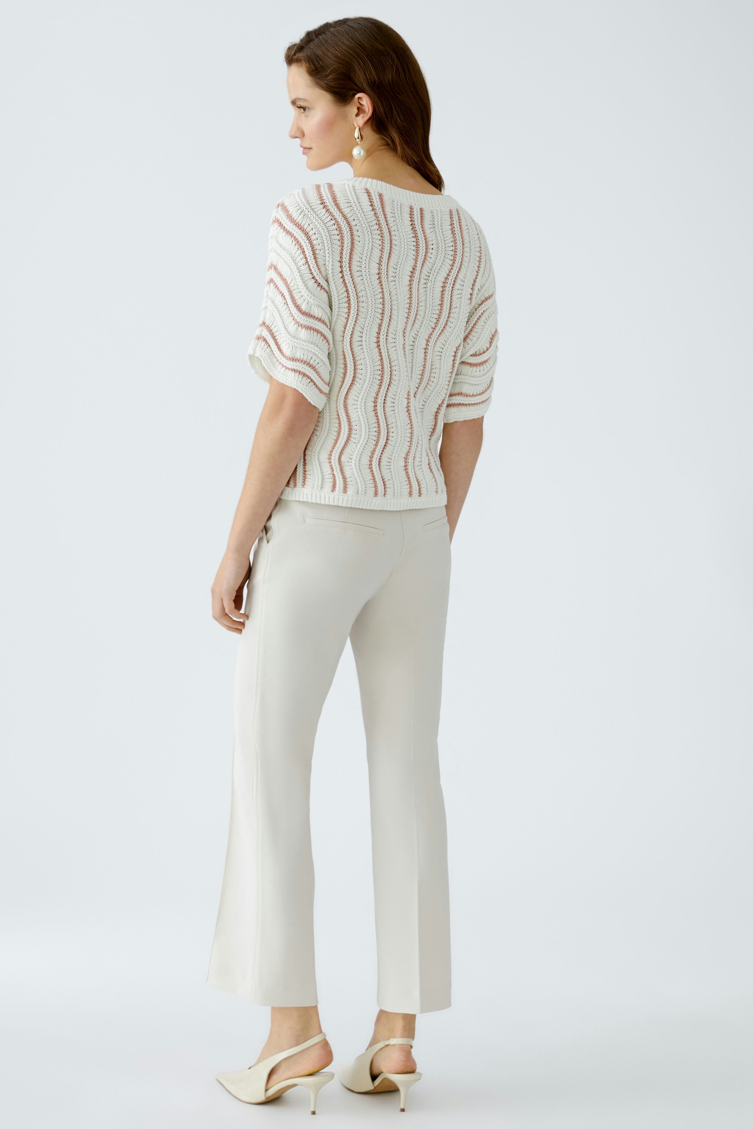 Stylish women's pullover: A woman in a light, patterned pullover paired with elegant trousers.