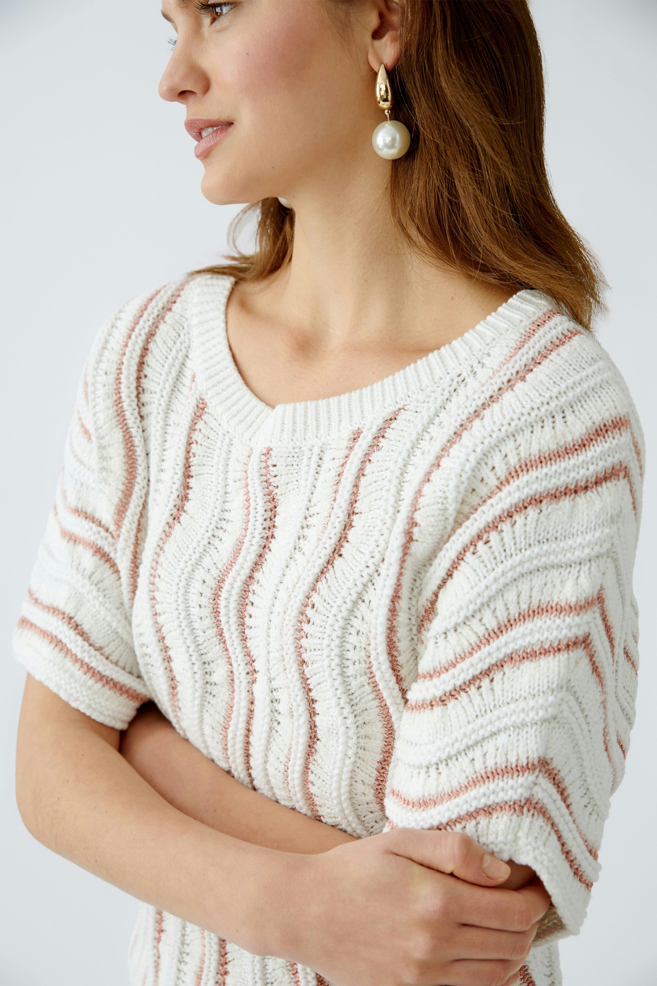 Stylish women's pullover: A woman in a cream and pink striped pullover, exuding casual elegance.