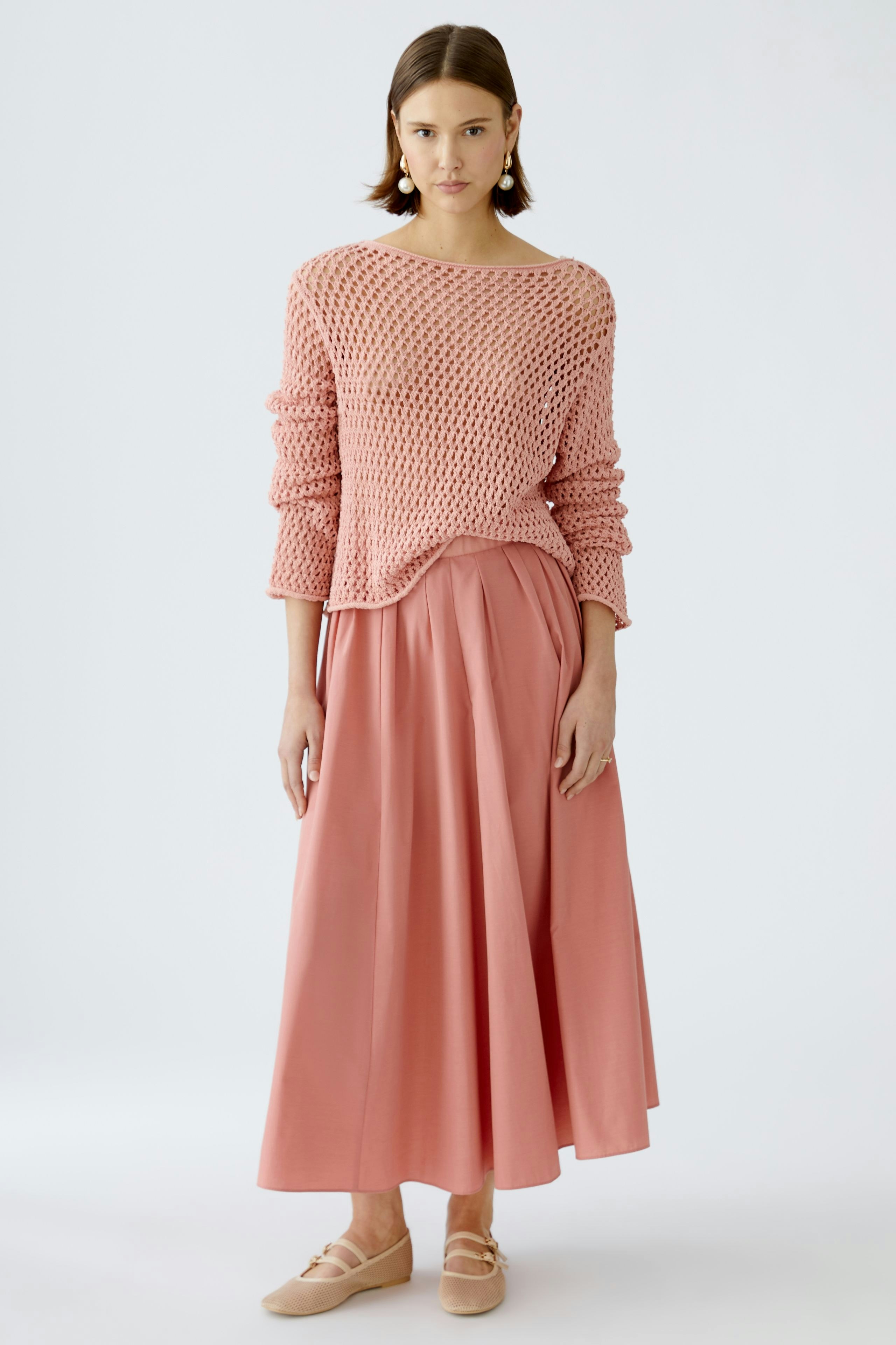 Stylish women's pullover: A woman in a pink knitted pullover paired with a flowing skirt.