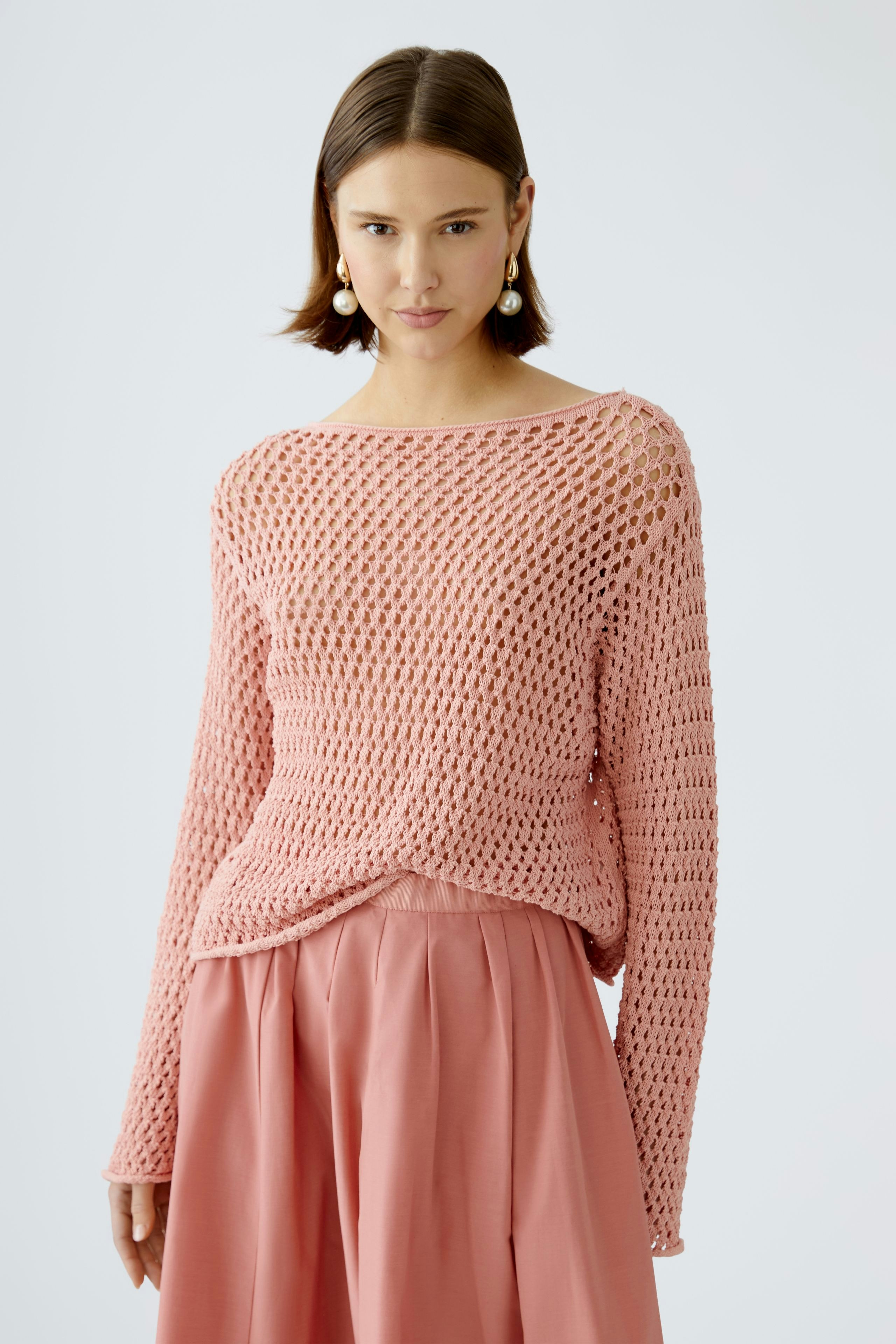 Stylish women's pullover: A woman in a pink open-knit pullover paired with a flowing skirt.
