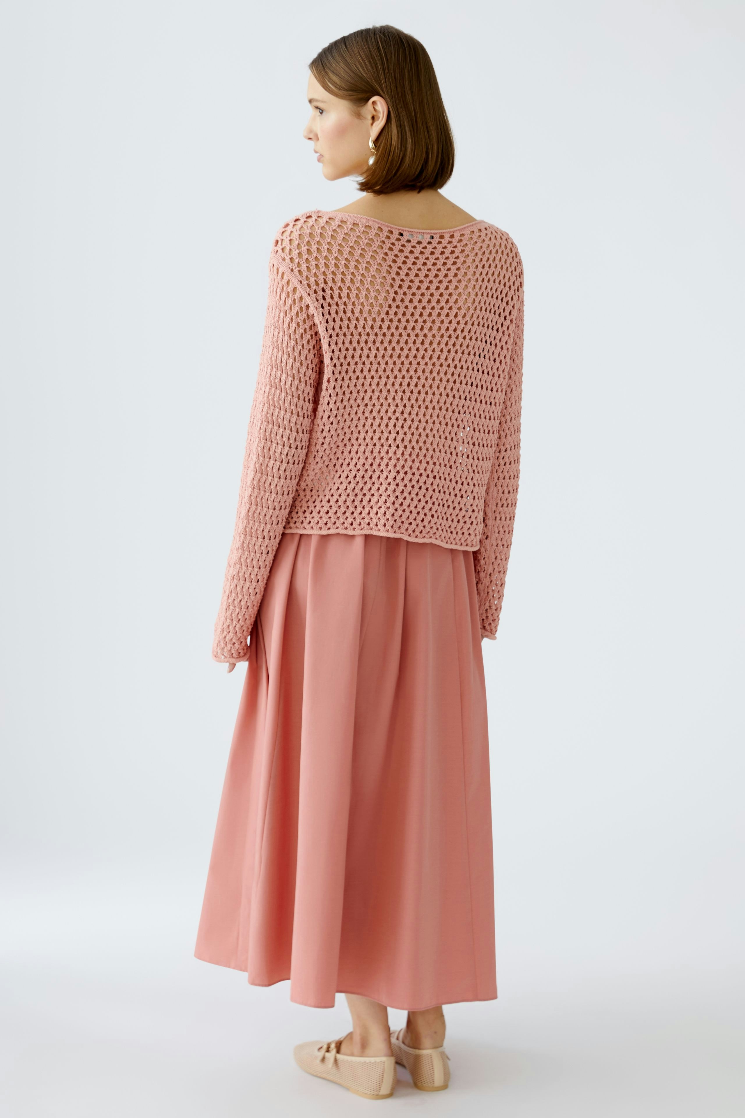 Stylish women's pullover: A woman in a pink open-knit pullover paired with a flowing skirt.