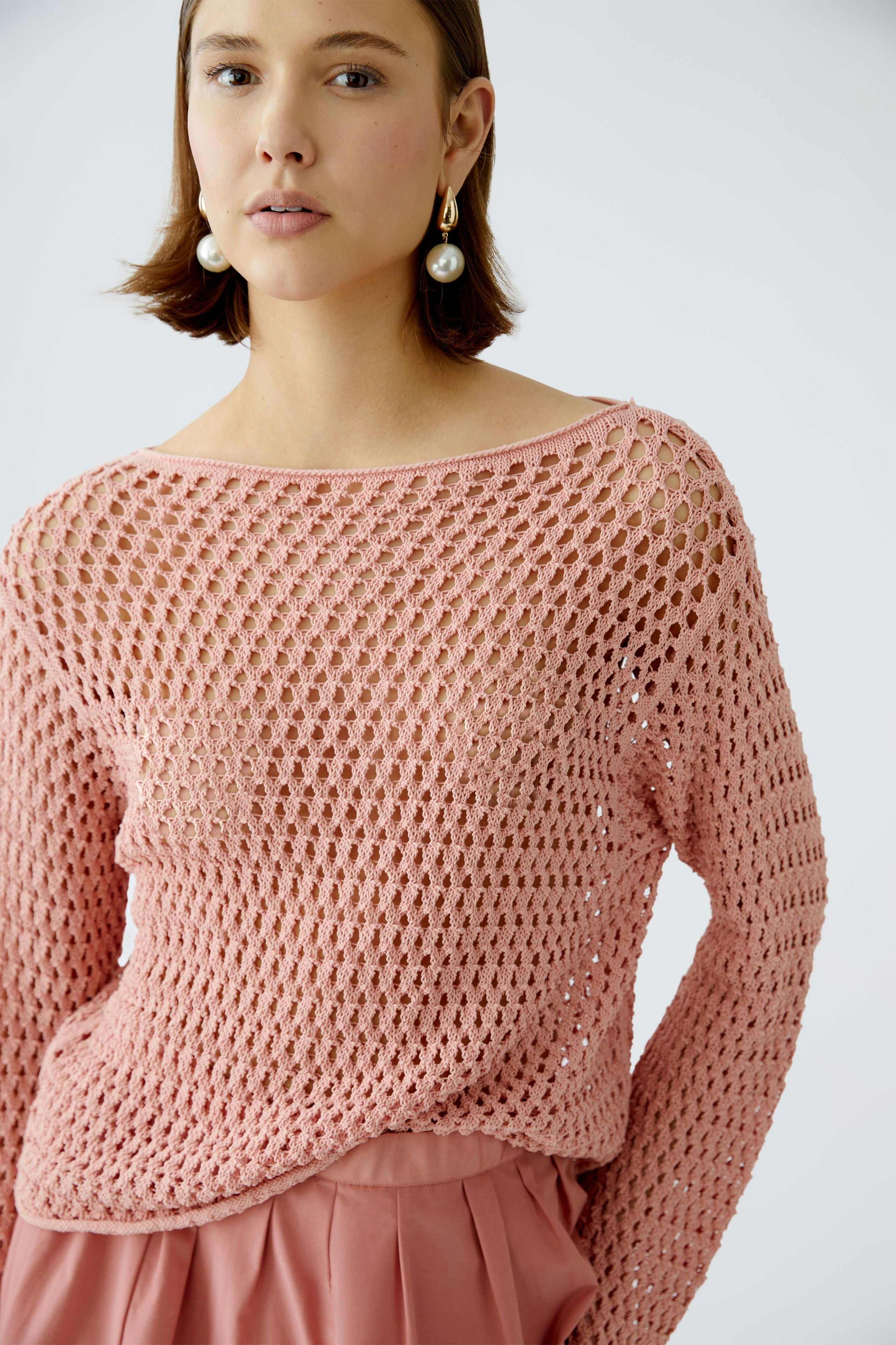 Stylish women's pullover: A woman in a pink open-knit pullover, exuding casual elegance.
