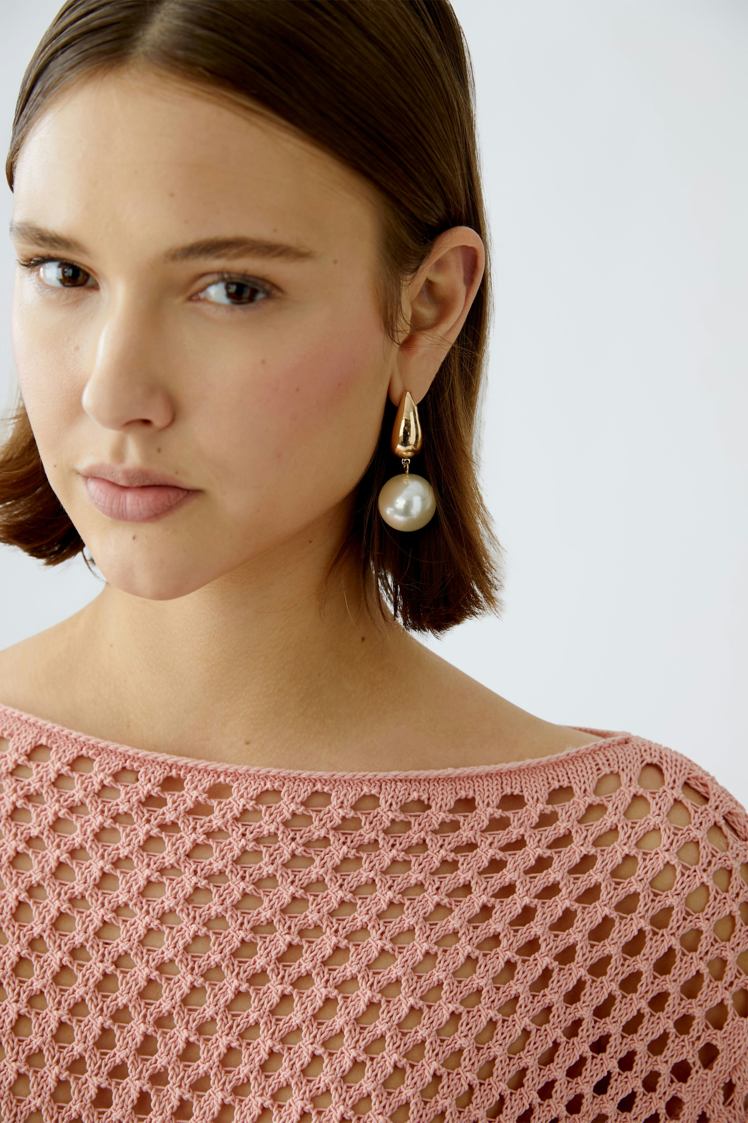 Stylish women's pullover: A woman in a pink open-knit pullover, showcasing a modern and elegant look.