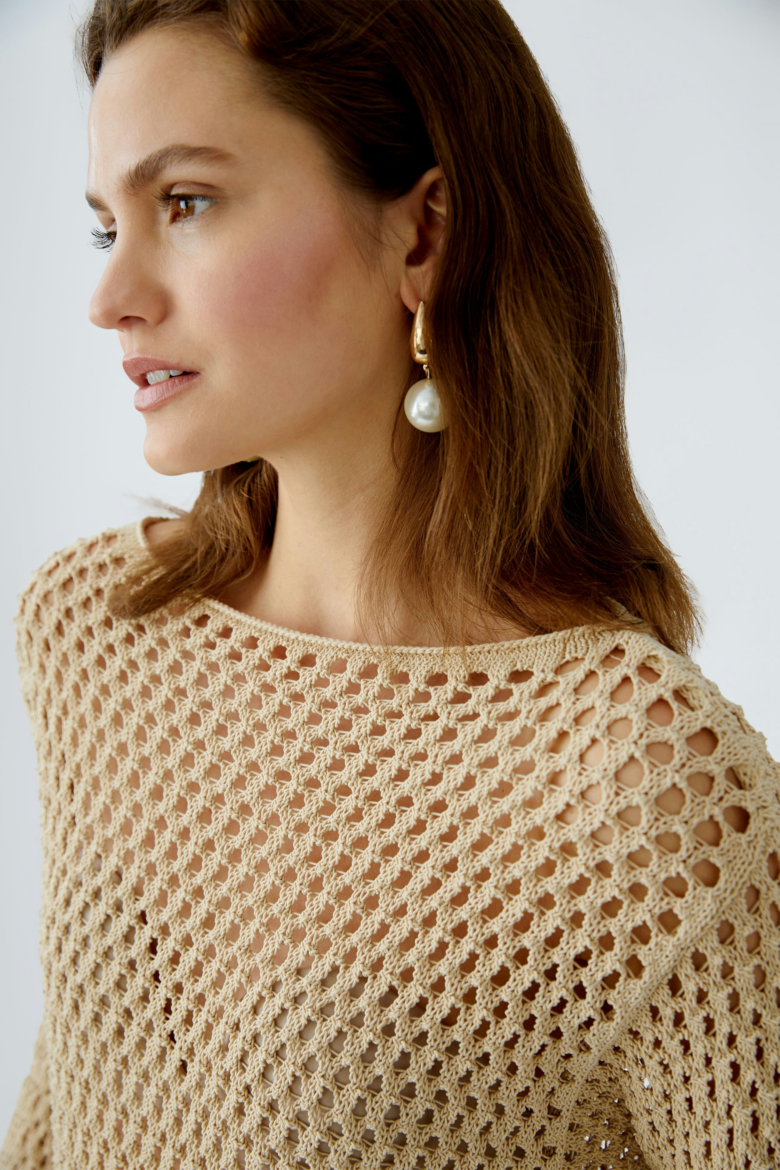 Eleganter Damen-Pullover: Frau in einem beigen, luftigen Strickpullover mit Netzstruktur.
