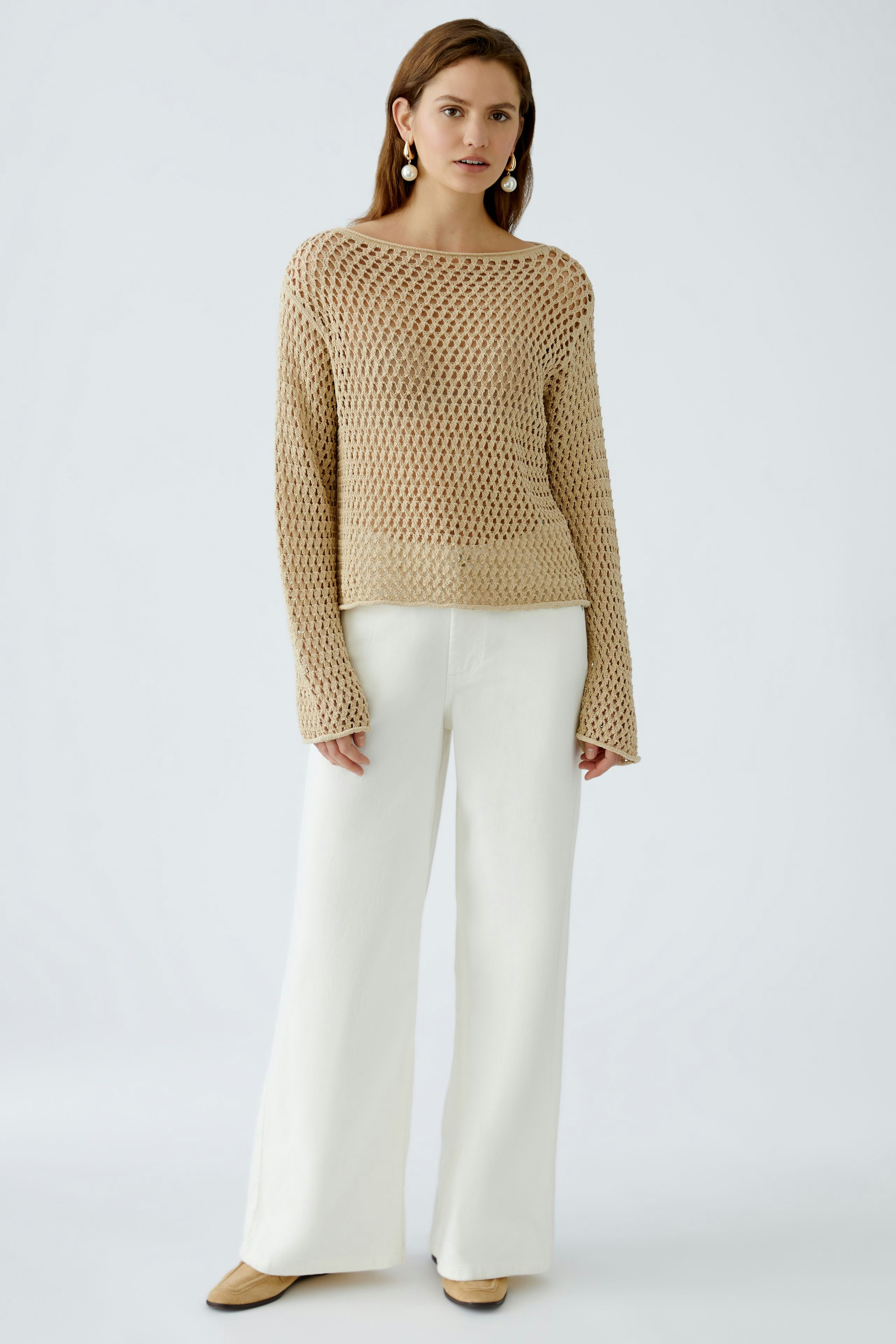 Damen-Pullover: Frau in beigem, luftigen Strickpullover mit weitem Schnitt und langen Ärmeln.