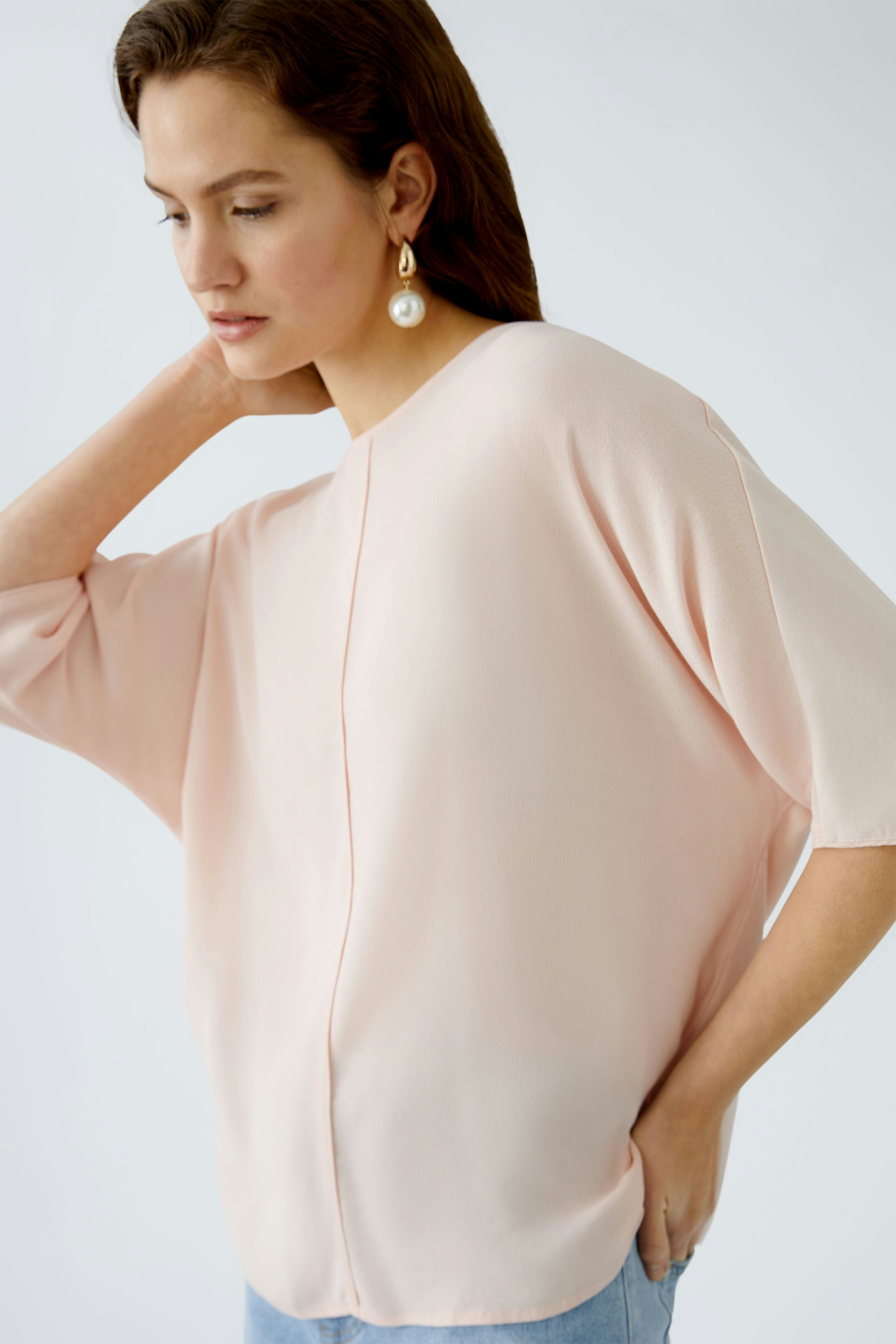 Elegantes Blusenshirt: Frau trägt ein zartrosa, lässiges Blusenshirt mit weiten Ärmeln.