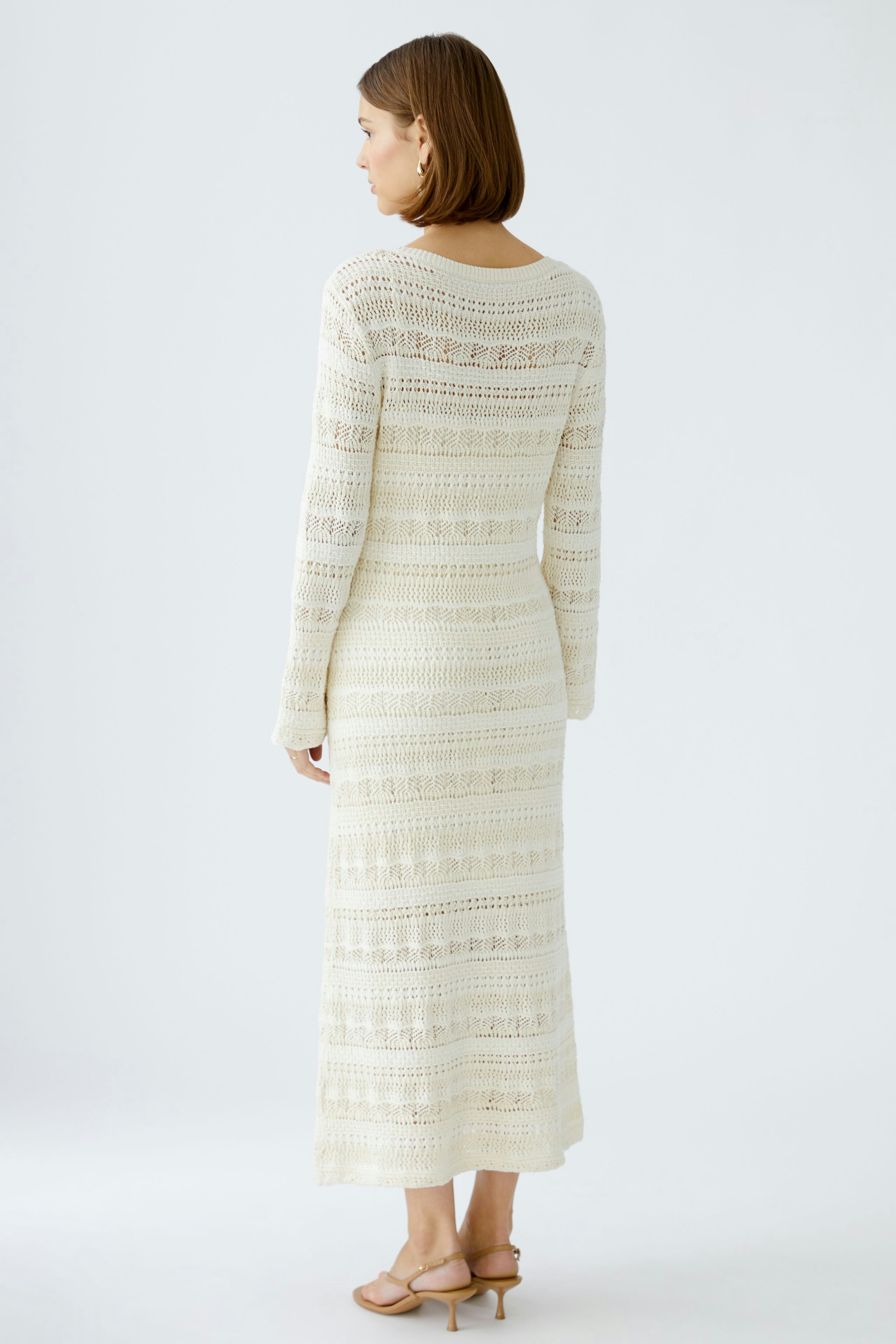 Elegantes Strickkleid: Frau in einem langen, hellen Strickkleid mit feinen Mustern von hinten.