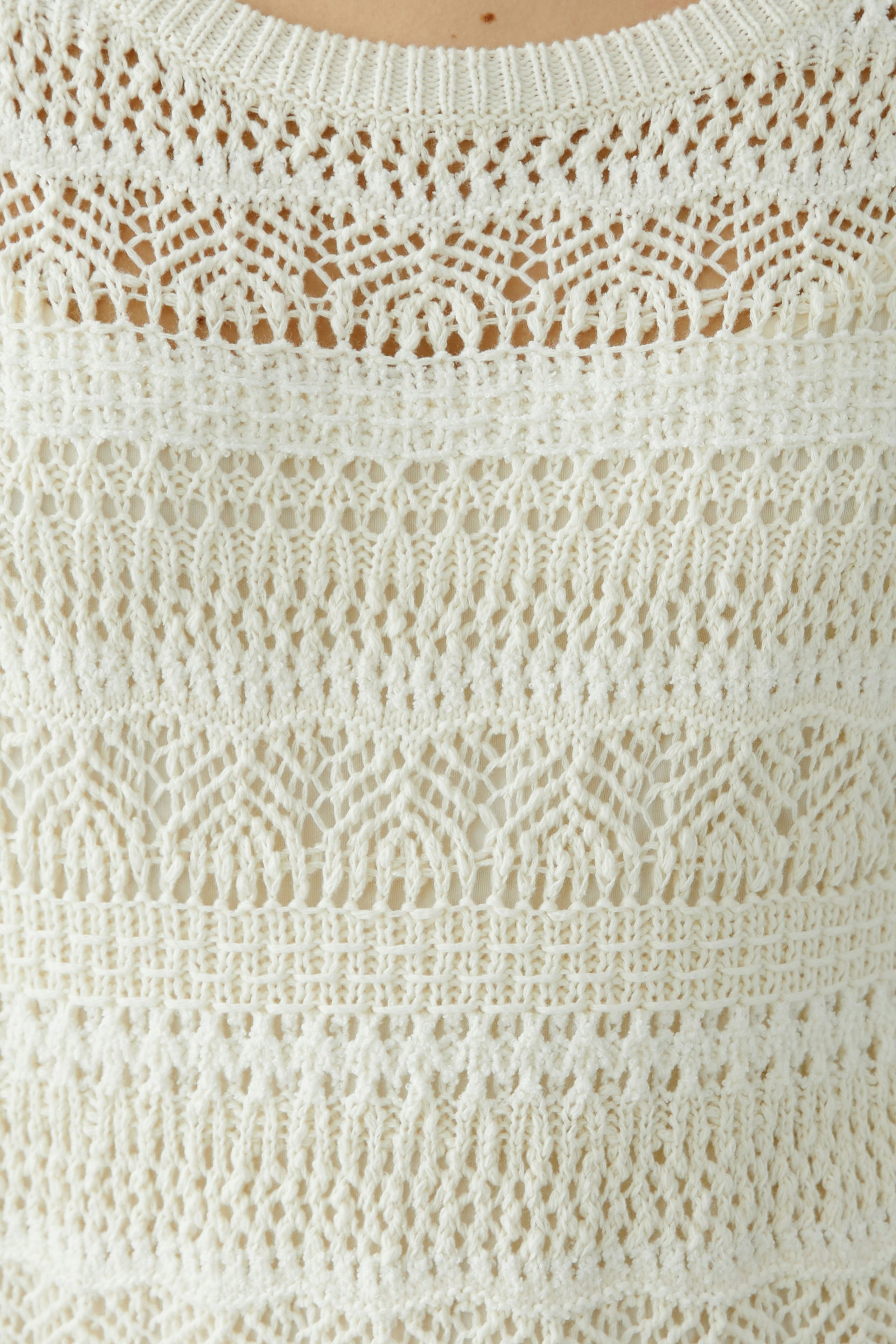 Elegantes Strickkleid: Frau in einem hellen, luftigen Strickkleid mit feinen Mustern.