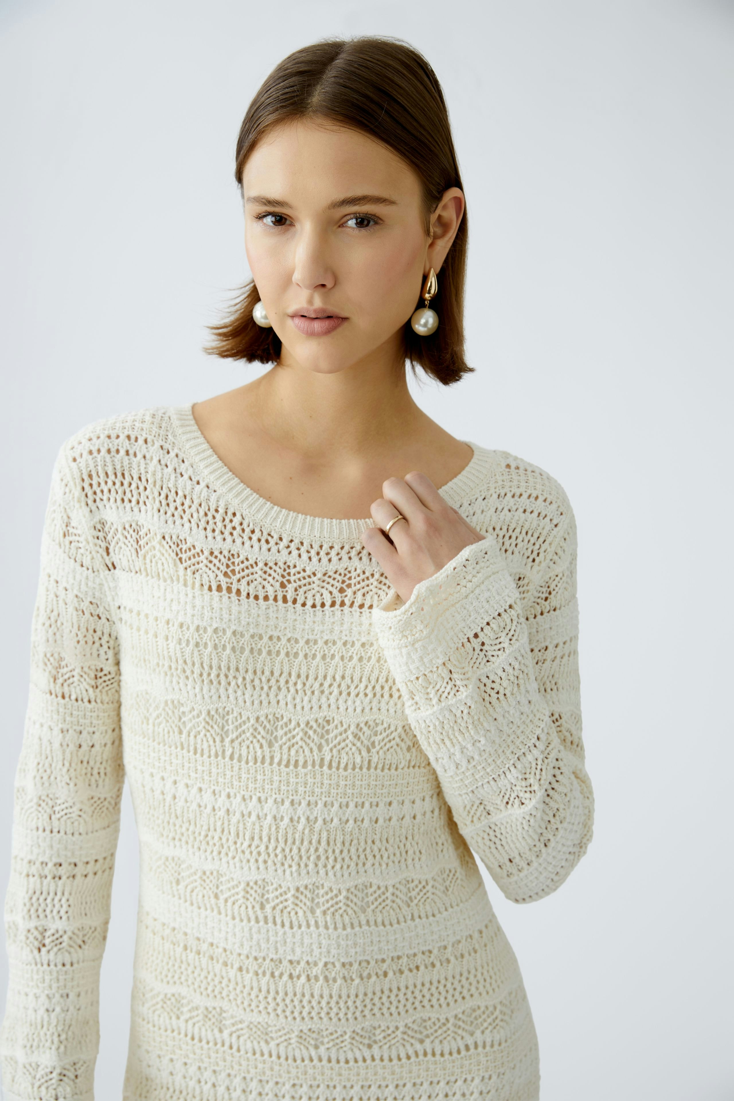 Elegantes Strickkleid: Junge Frau in einem hellen, strukturierten Strickkleid mit langen Ärmeln.