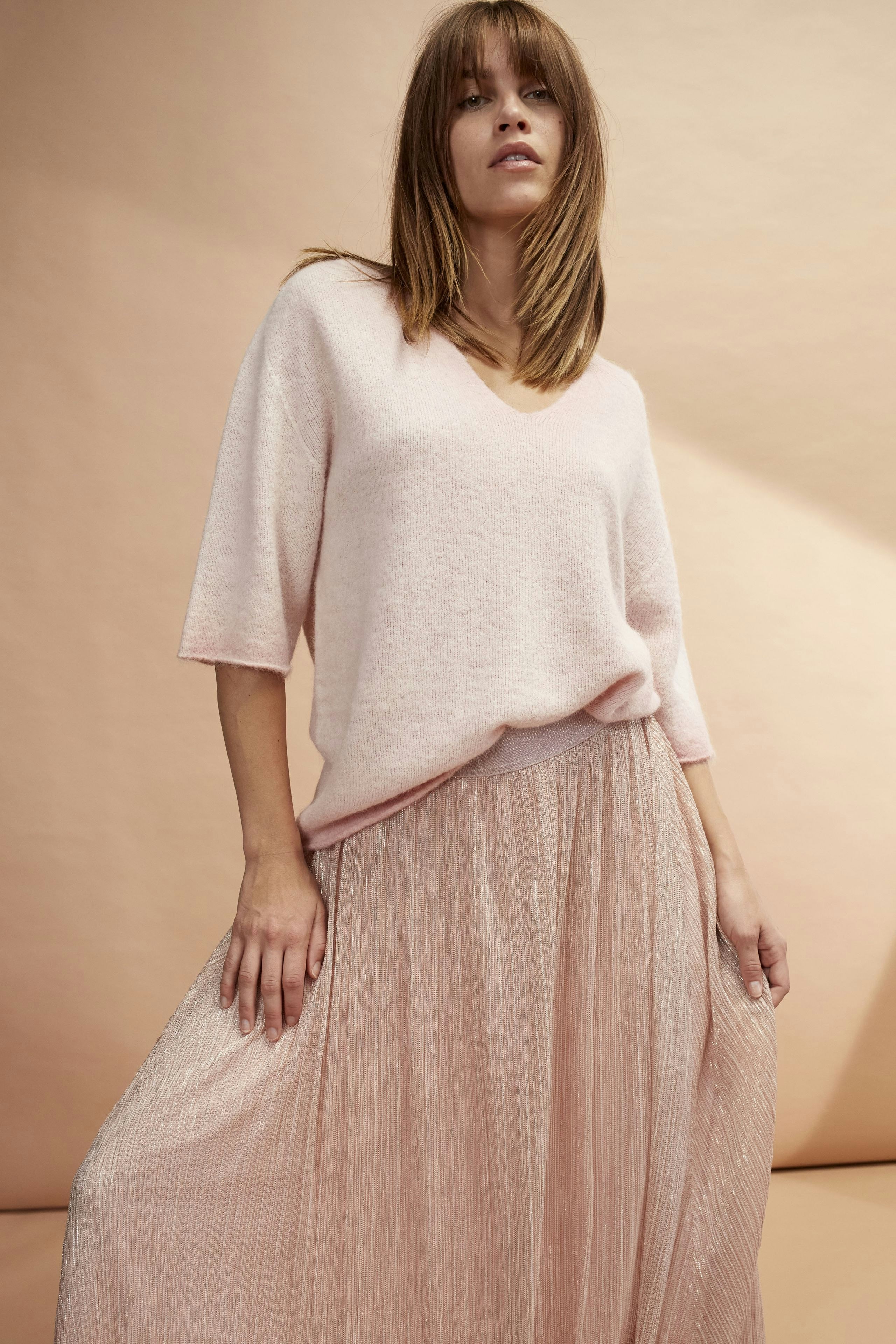 Eleganter Maxirock: Frau trägt einen fließenden, rosafarbenen Maxirock mit plissierten Details.